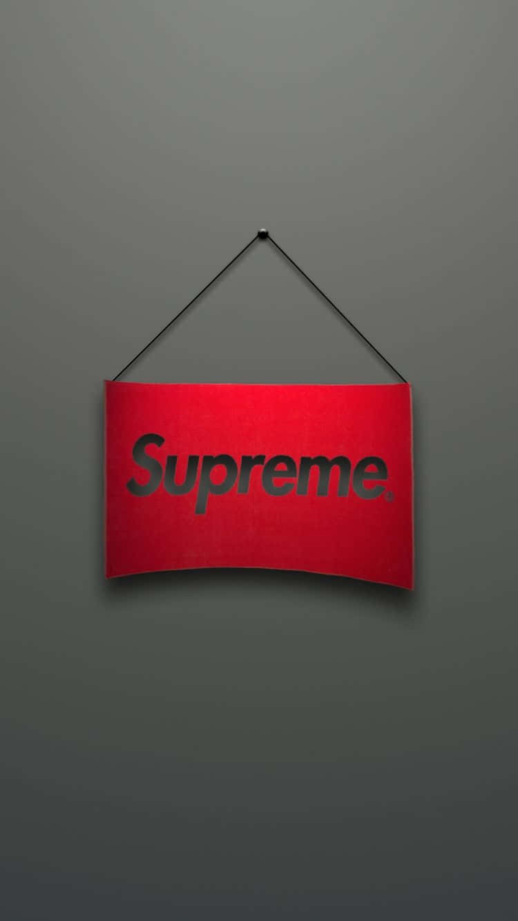 supreme aesthetic 桌布 壁紙 — 一個紅色Supreme標誌牌用黑色繩子掛在純灰色牆壁中央。