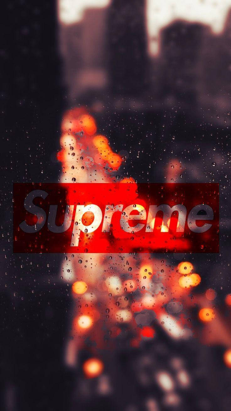 超屌 Supreme 桌布 壁紙 — 一個紅色Supreme標誌透過沾滿雨水的窗戶發光，窗外是夜晚模糊的城市景觀。