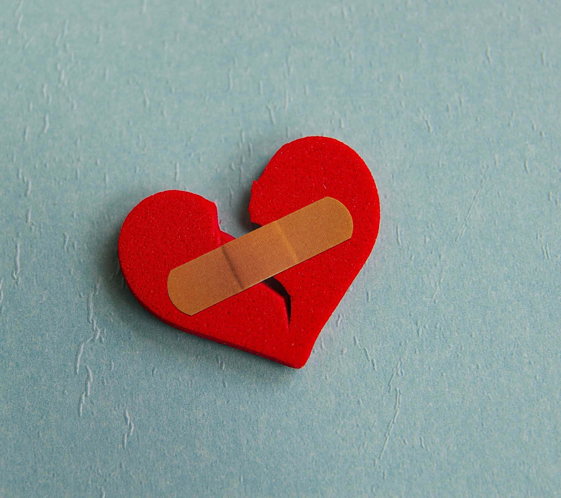 Aesthetic Heart 桌布 壁紙 — 一個紅色不織布心形，邊緣破損，用米色膠布貼在帶紋理的淺藍色表面上。