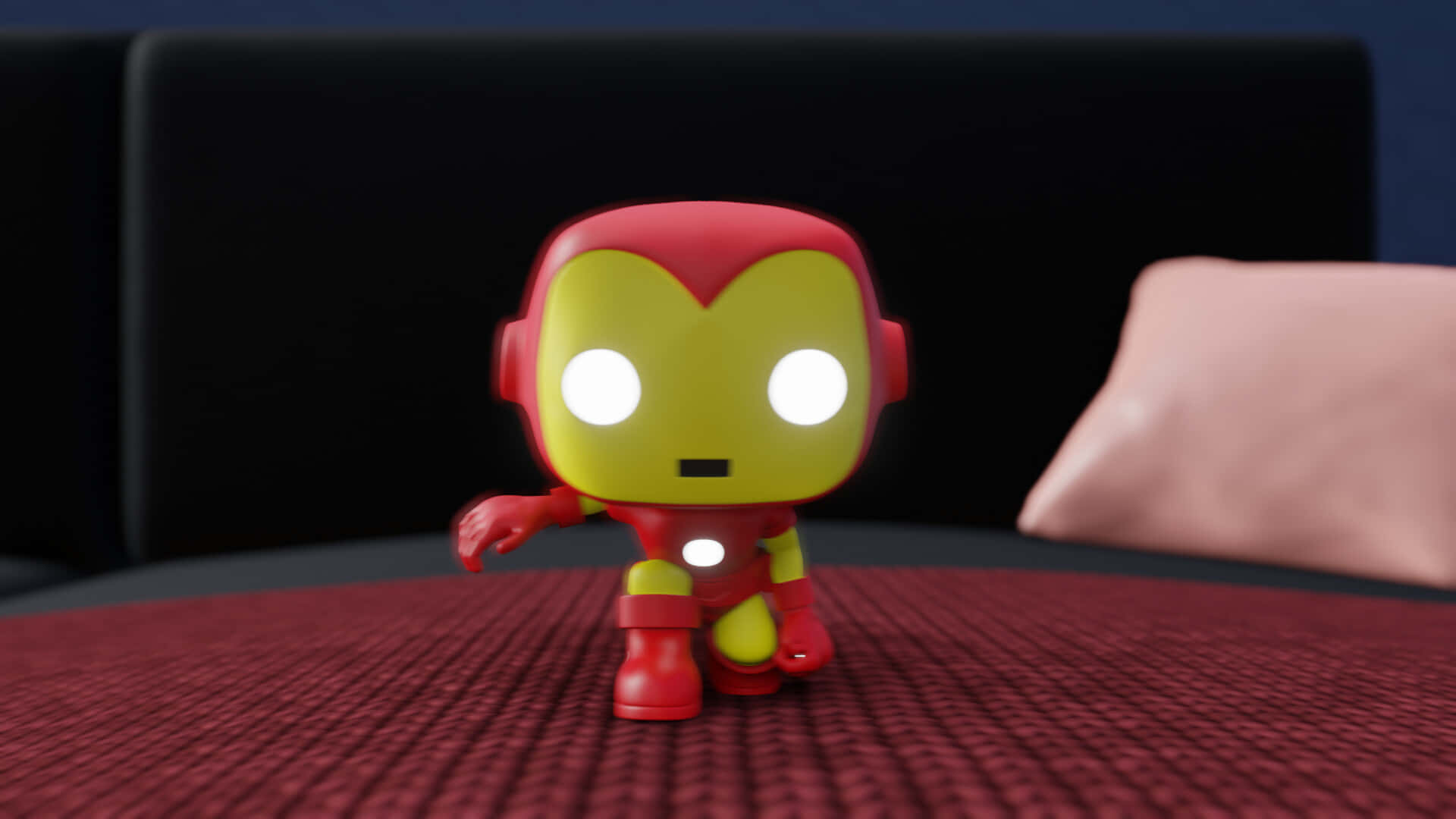 Iron Man Pop Figures 桌布 壁紙 — 一個紅色和金色的鋼鐵人Funko Pop!人偶站在有紋理的紅色表面上，眼睛發光，背景有黑色沙發。