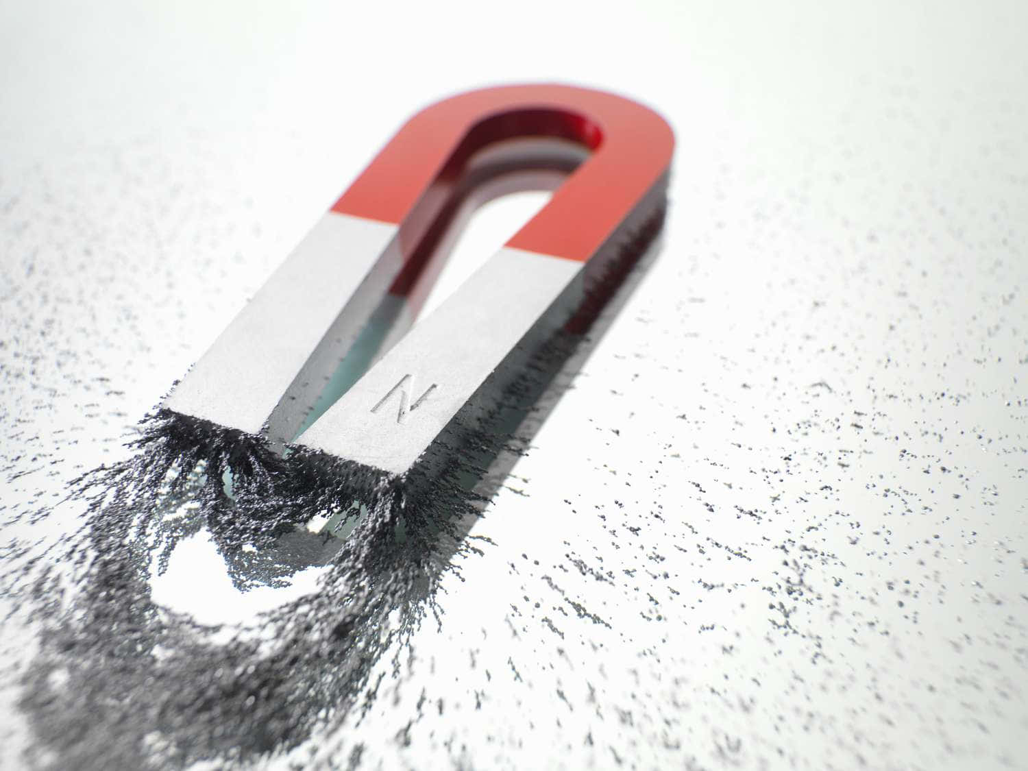 Material 桌布 壁紙 — 一個紅色和銀色的U形磁鐵吸引白色表面上的鐵屑，揭示其磁場。
