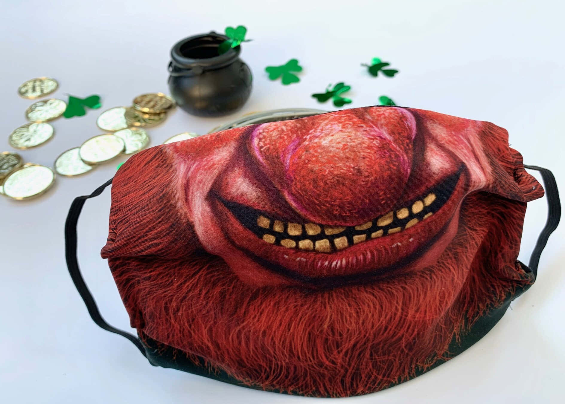 Leprechaun 桌布 壁紙 — 一個紅色妖精主題面具，咧嘴大笑，露出金牙，旁邊放著一鍋金幣和三葉草。
