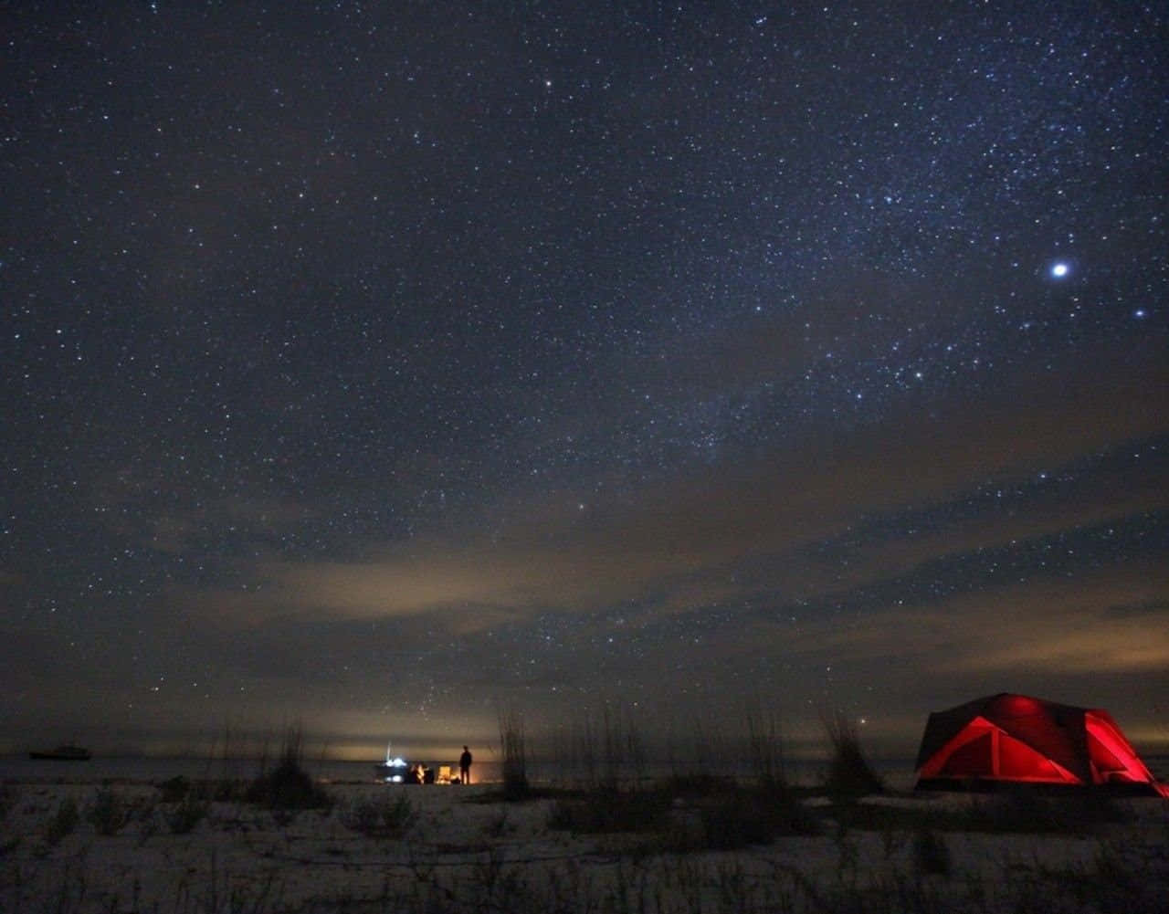 Beach Camping 桌布 壁紙 — 一個紅色帳篷在廣闊的星空下溫暖地發光，淡淡的銀河雲飄過雪白的沙灘。
