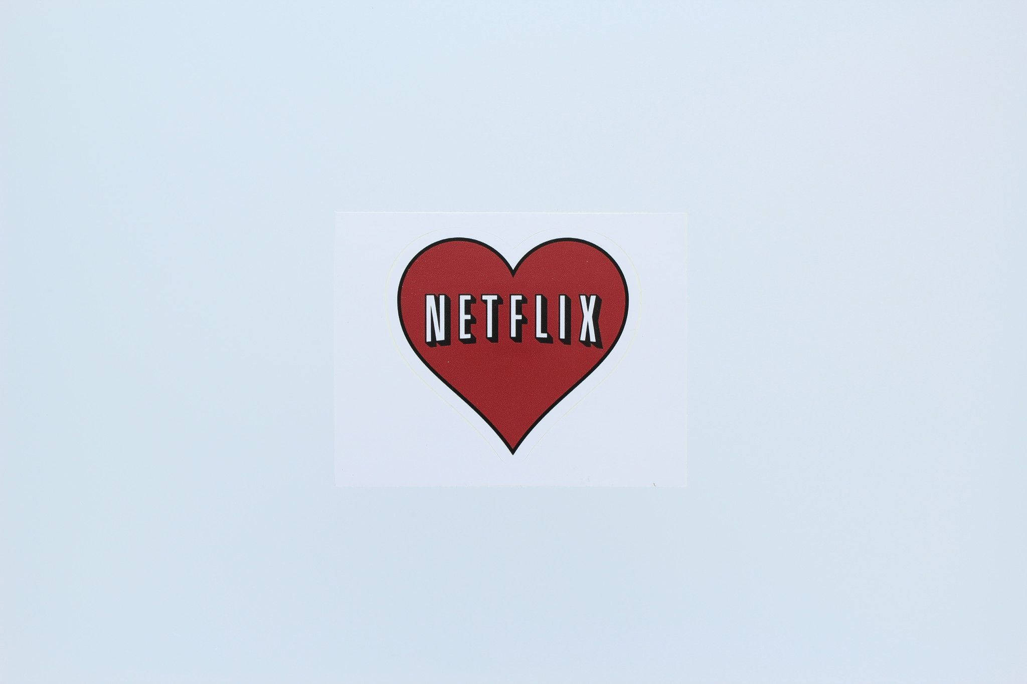 Netflix 桌布 壁紙 — 一個紅色心形Netflix標誌貼紙，置於純淺藍色背景中央。