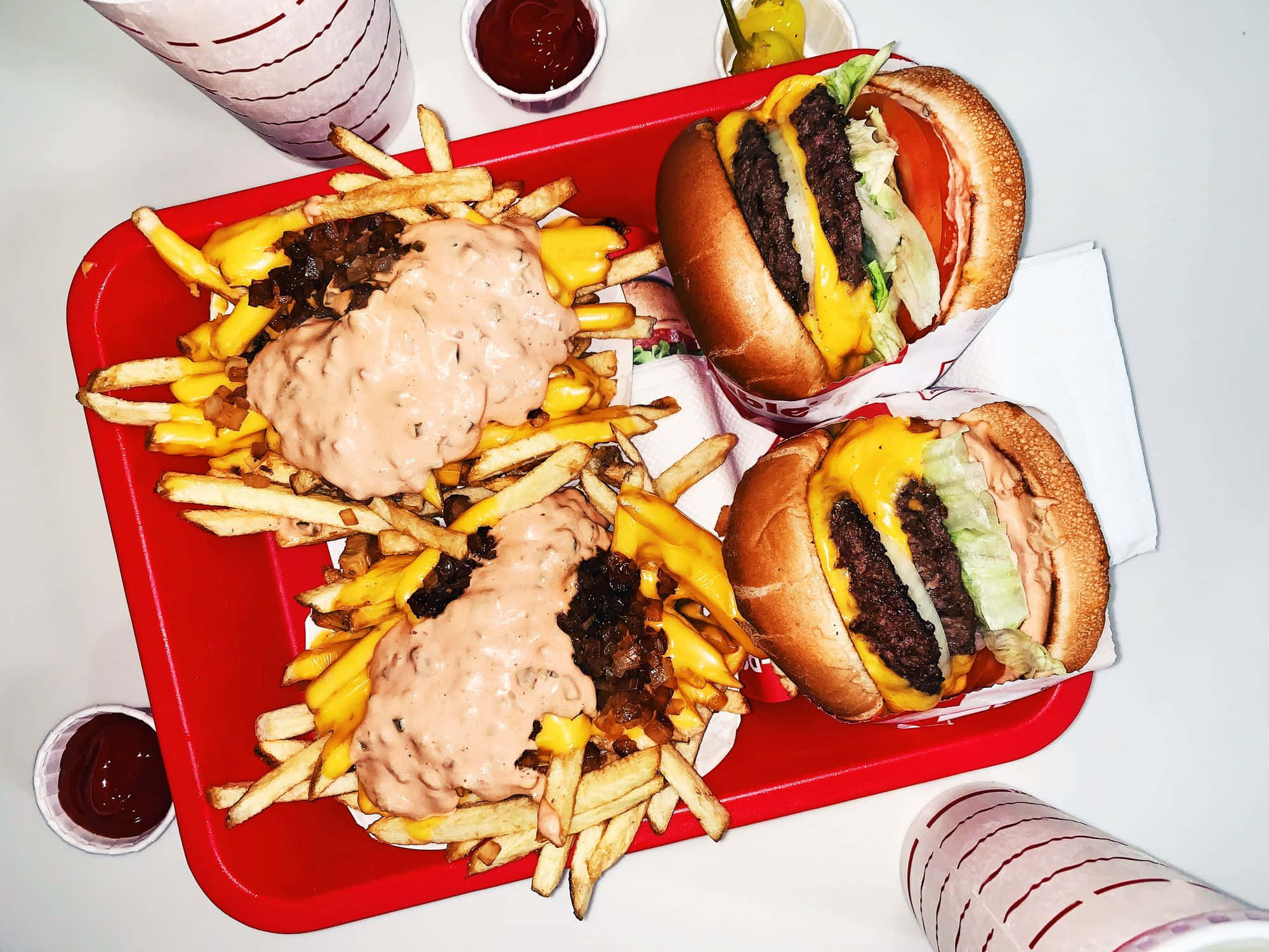 fast food 桌布 壁紙 — 一個紅色托盤上放著兩個起司漢堡和兩堆淋上奶油醬汁和洋蔥的薯條。
