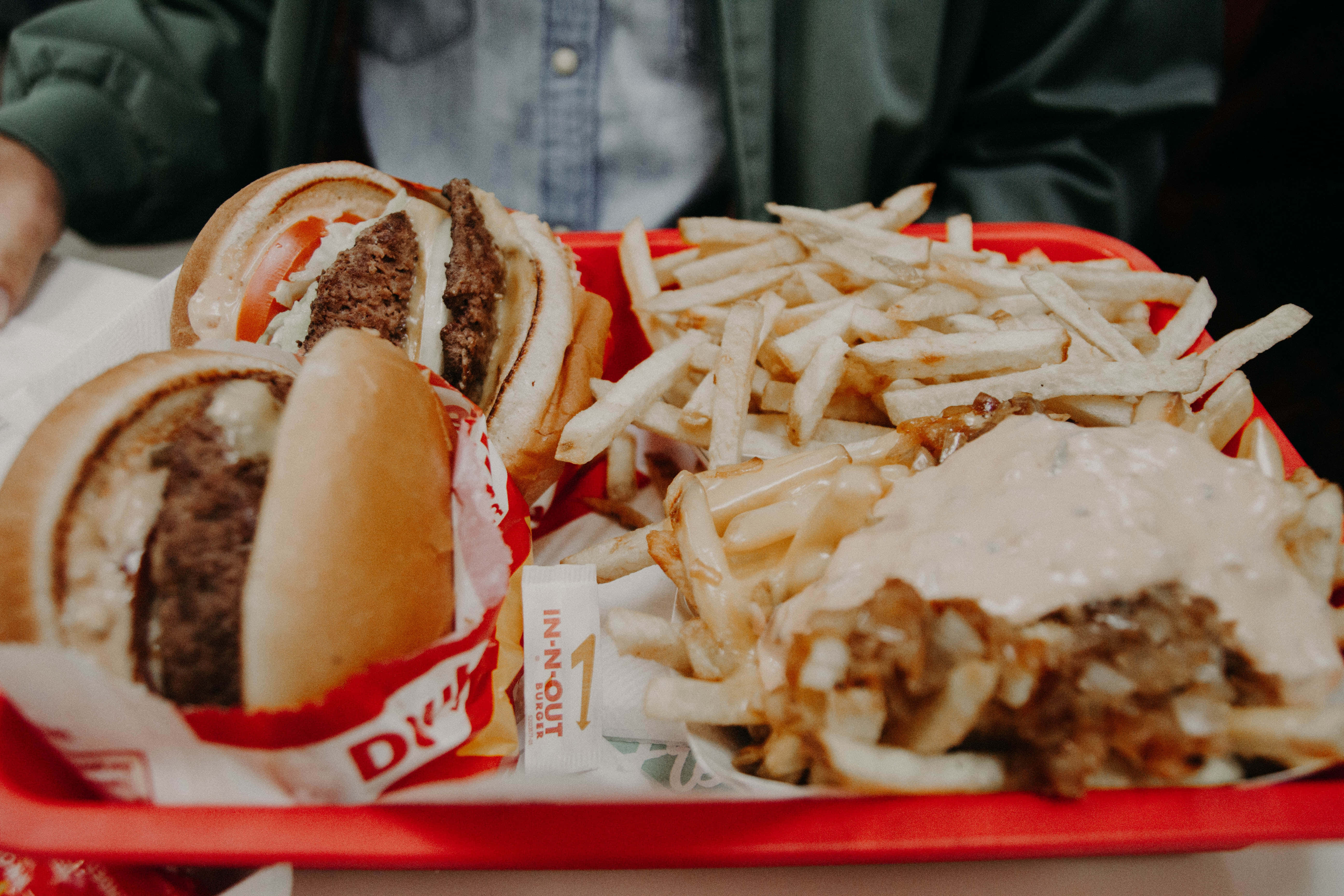 fast food 桌布 壁紙 — 一個紅色托盤的特寫，上面放著兩個 In-N-Out 漢堡和一堆沾有醬汁的薯條。