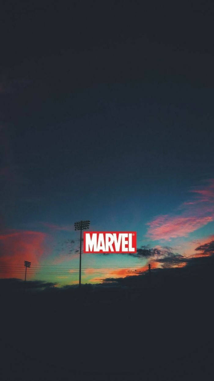 雲朵 桌布 壁紙 — 一個紅色的Marvel標誌在由火辣橙色、粉紅色和深藍色雲彩繪畫的暮色天空下大膽聳立。