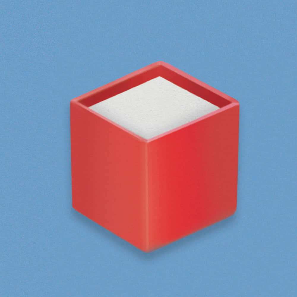 Block 桌布 壁紙 — 一個紅色立方體，內部有白色泡沫，居中放置在帶有柔和陰影的純藍色背景上。