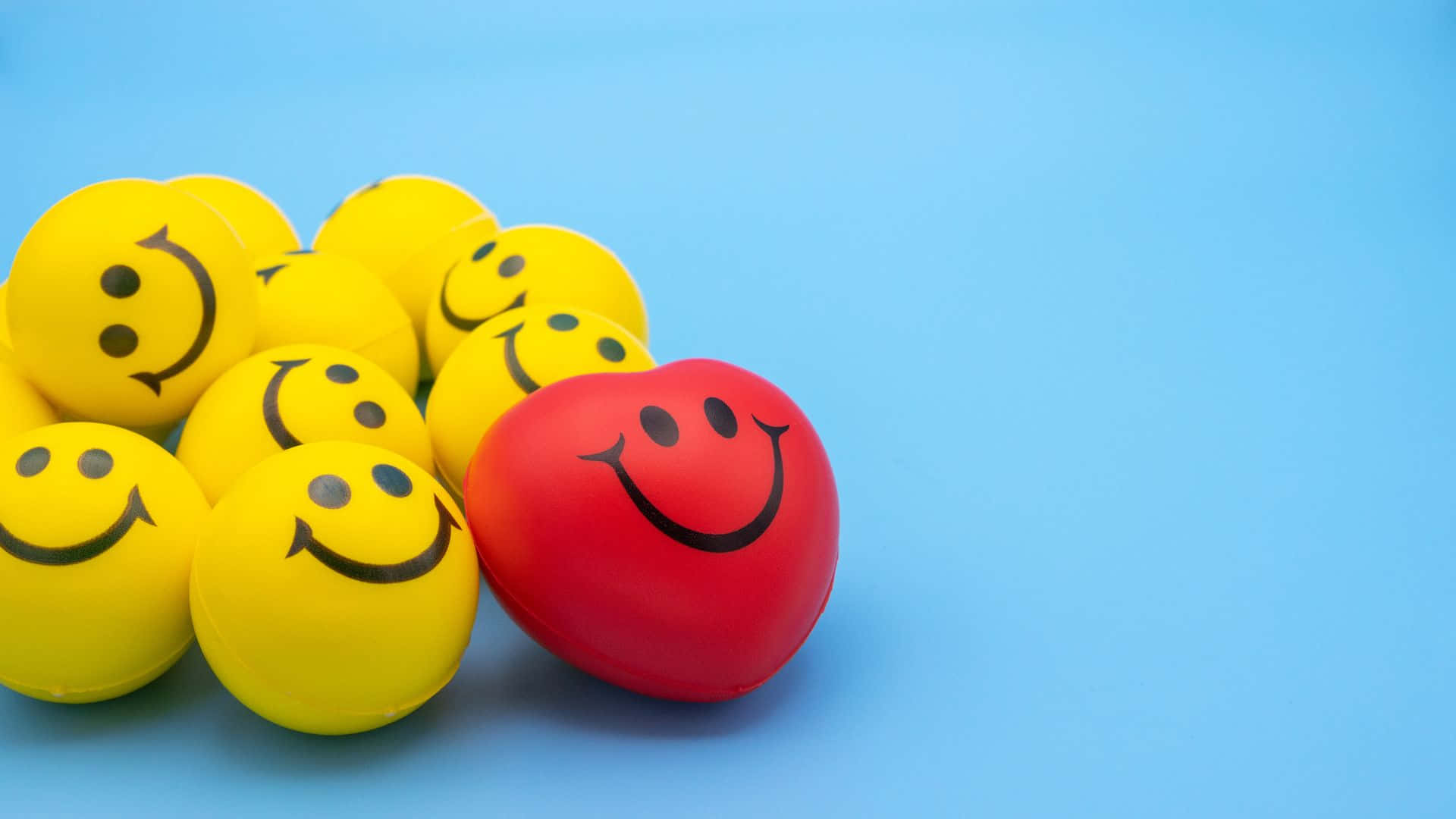 Smiley 桌布 壁紙 — 一個紅色笑臉球在純藍色背景上的一群黃色笑臉球中脫穎而出。