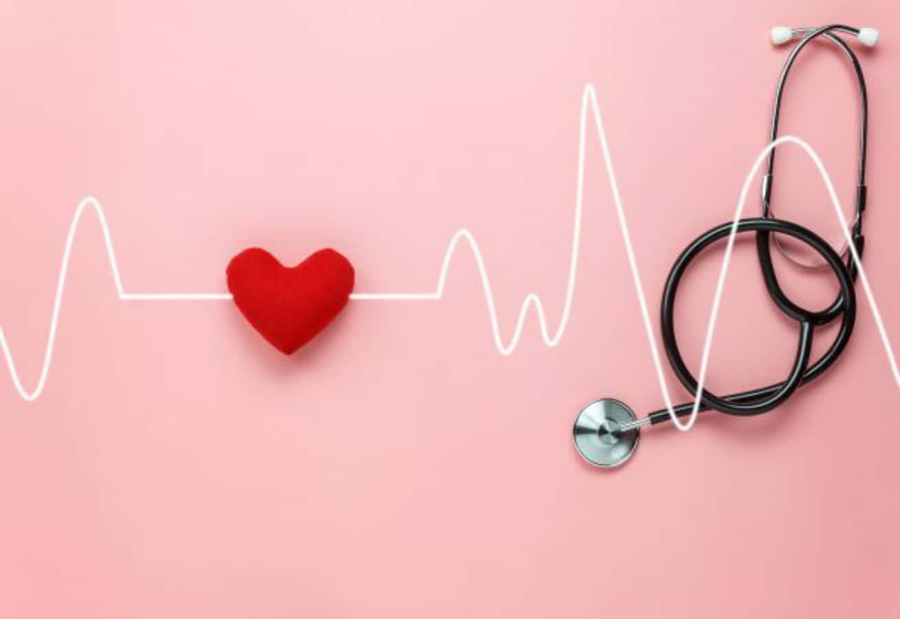Heartbeat 桌布 壁紙 — 一個紅色絨布心形放在白色心跳線上，旁邊有一個黑色聽診器，背景是柔和的粉紅色。