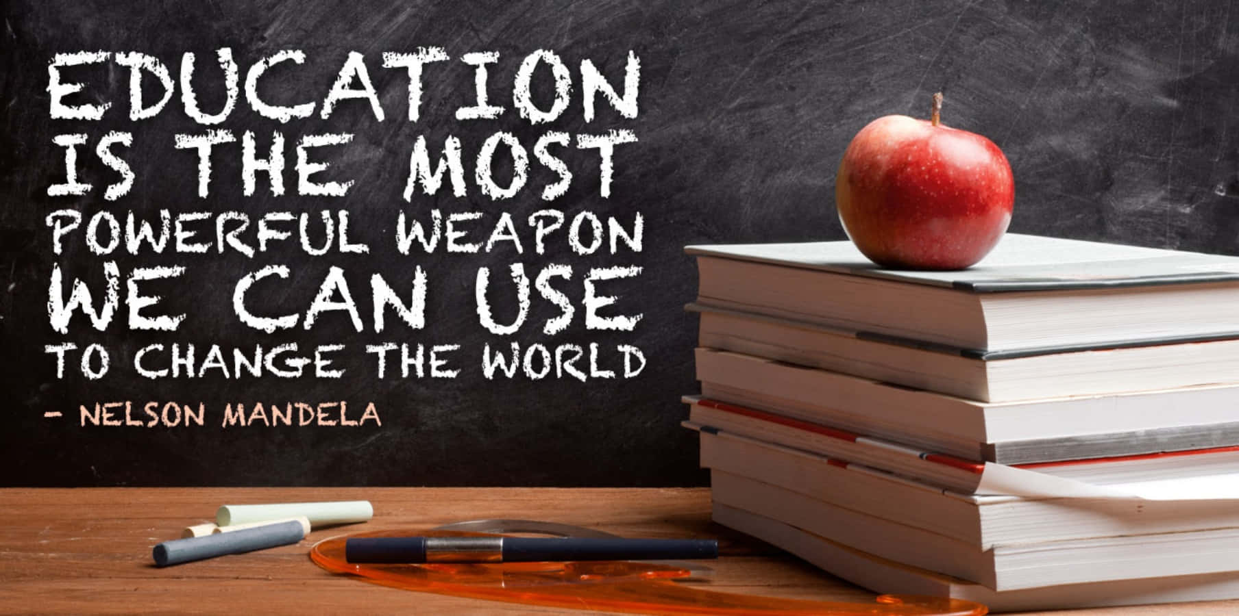 Education 桌布 壁紙 — 一個紅蘋果放在木桌上的一堆書上，後面的黑板上寫著關於教育的名言。