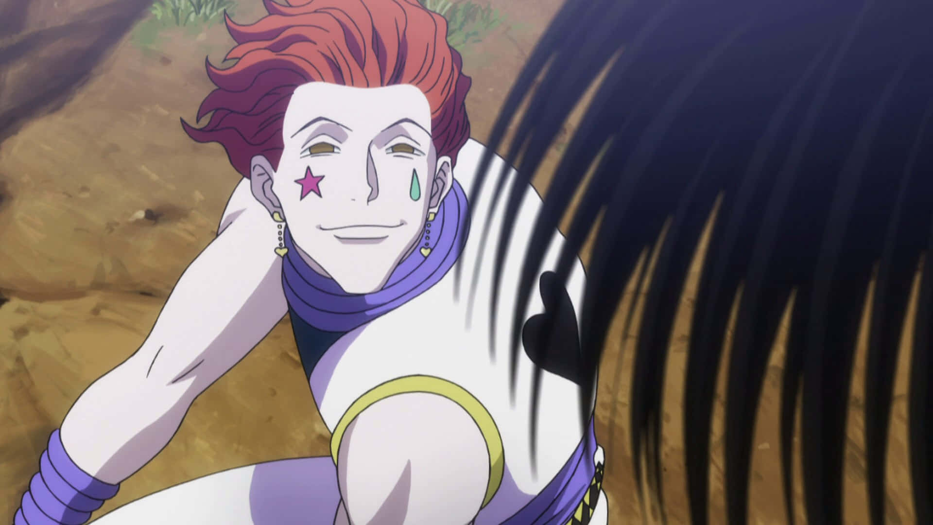 Hisoka Morow 桌布 壁紙 — 一個紅髮動漫角色，臉上畫有星星和淚珠圖案，在沙地中蹲下微笑。