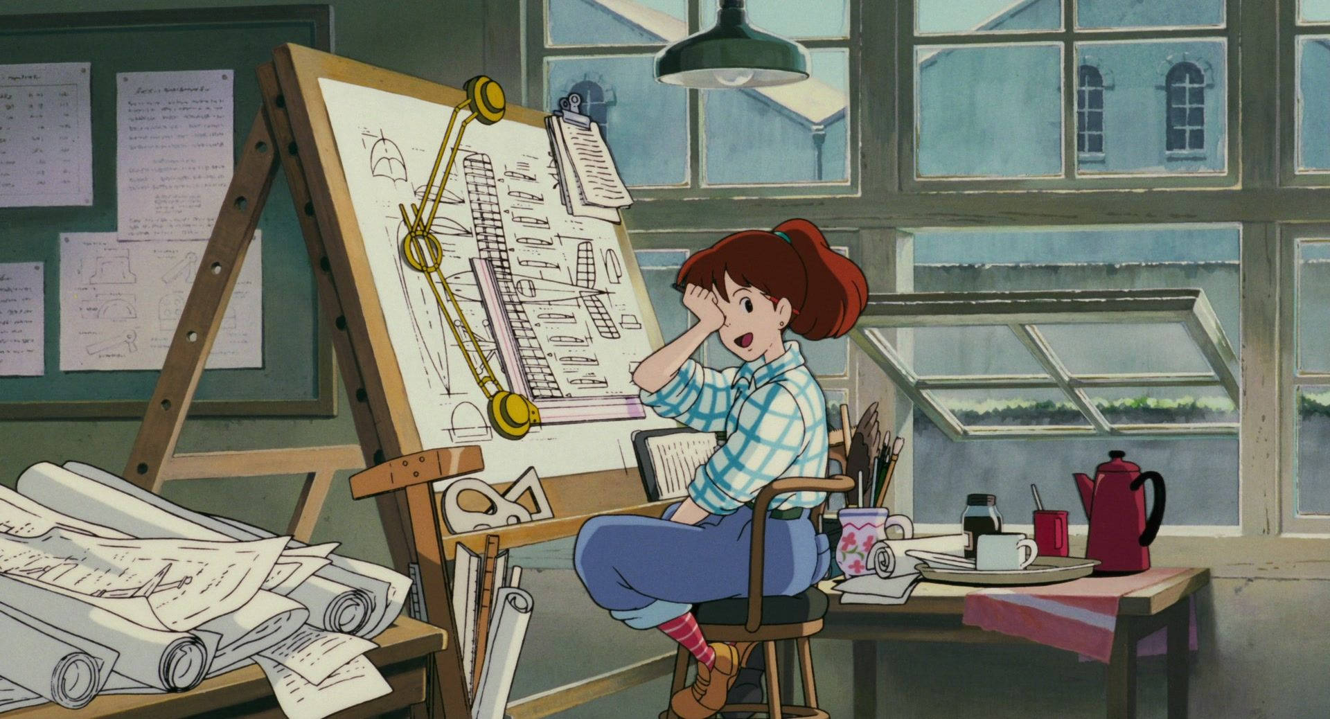 Studio 桌布 壁紙 — 一個紅髮女孩坐在陽光充足的畫室裡，周圍是雜亂的藍圖和美術用品，她驚訝地看著自己的作品。