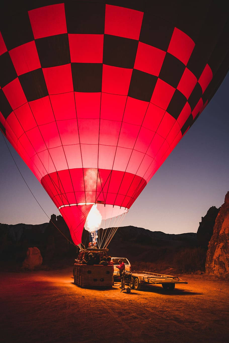 Hot Air Balloon 桌布 壁紙 — 一個紅黑格紋的熱氣球在暮色天空下溫暖地發光，準備起飛。