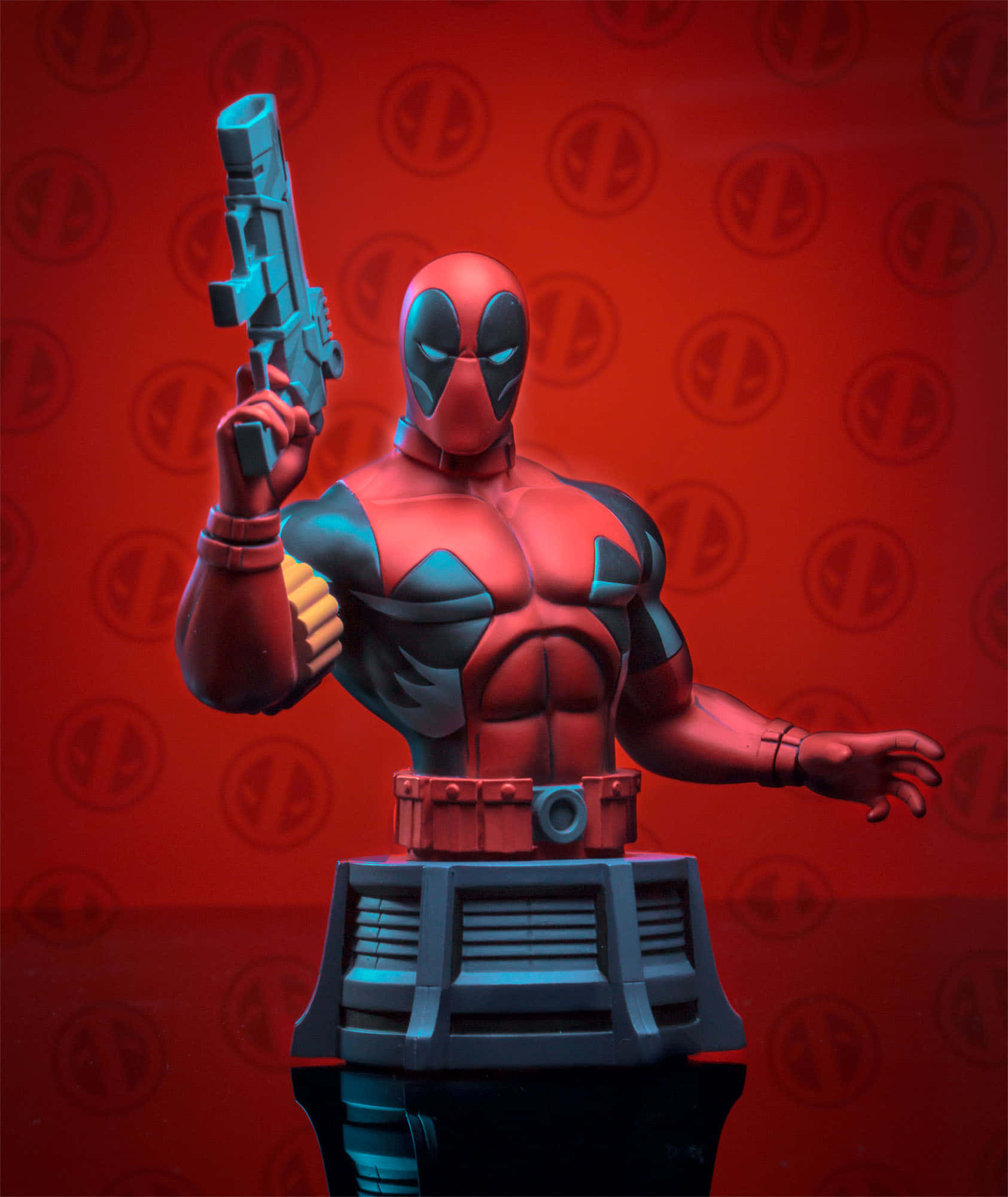 Deadpool Logo 桌布 壁紙 — 一個紅黑色死侍半身雕像，手持藍色槍枝，背景為重複標誌圖案。