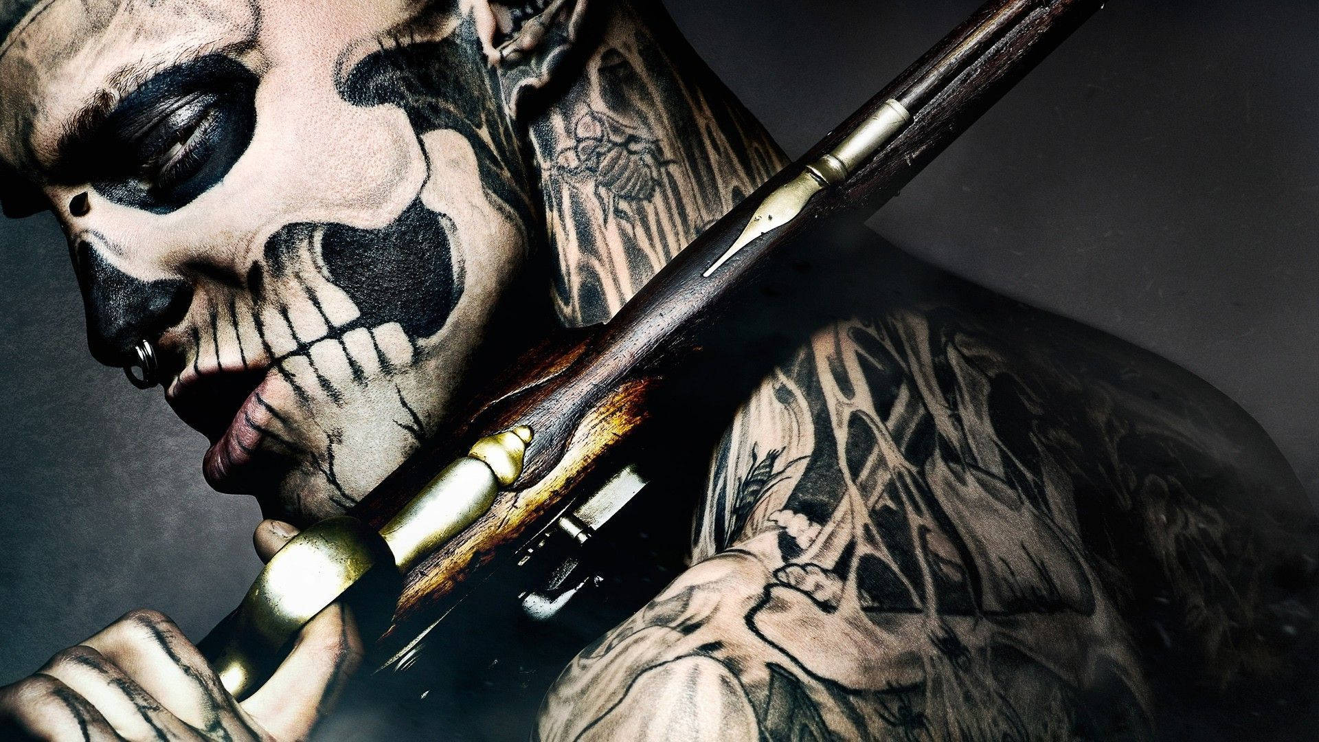 Tattoo 桌布 壁紙 — 一個紋身濃密、臉上畫著骷髏妝的男人在黑暗背景下拿著步槍。