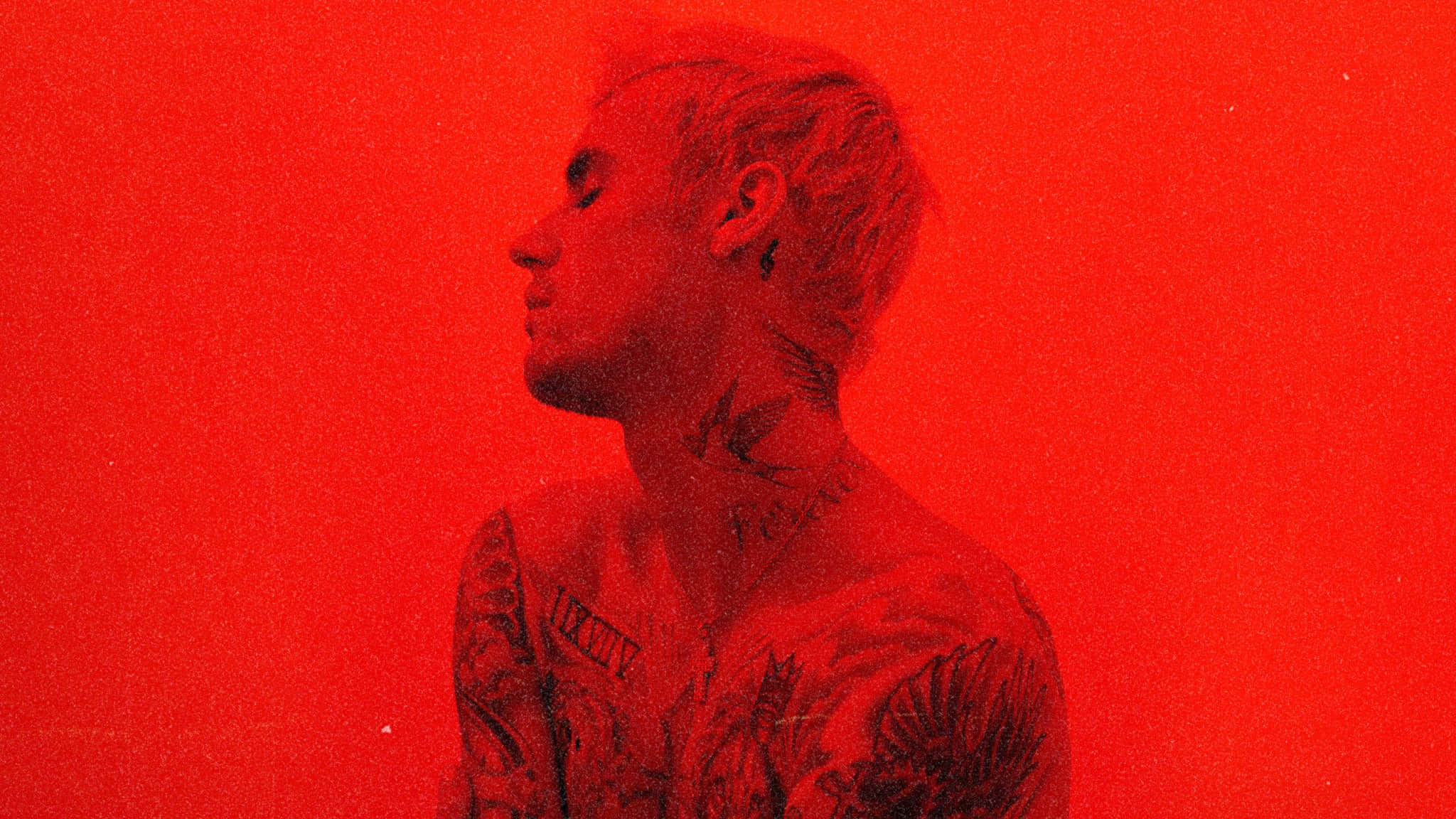 Justin Bieber 2021 桌布 壁紙 — 一個紋身男子側面，沐浴在強烈的紅光中，背景為純紅色。