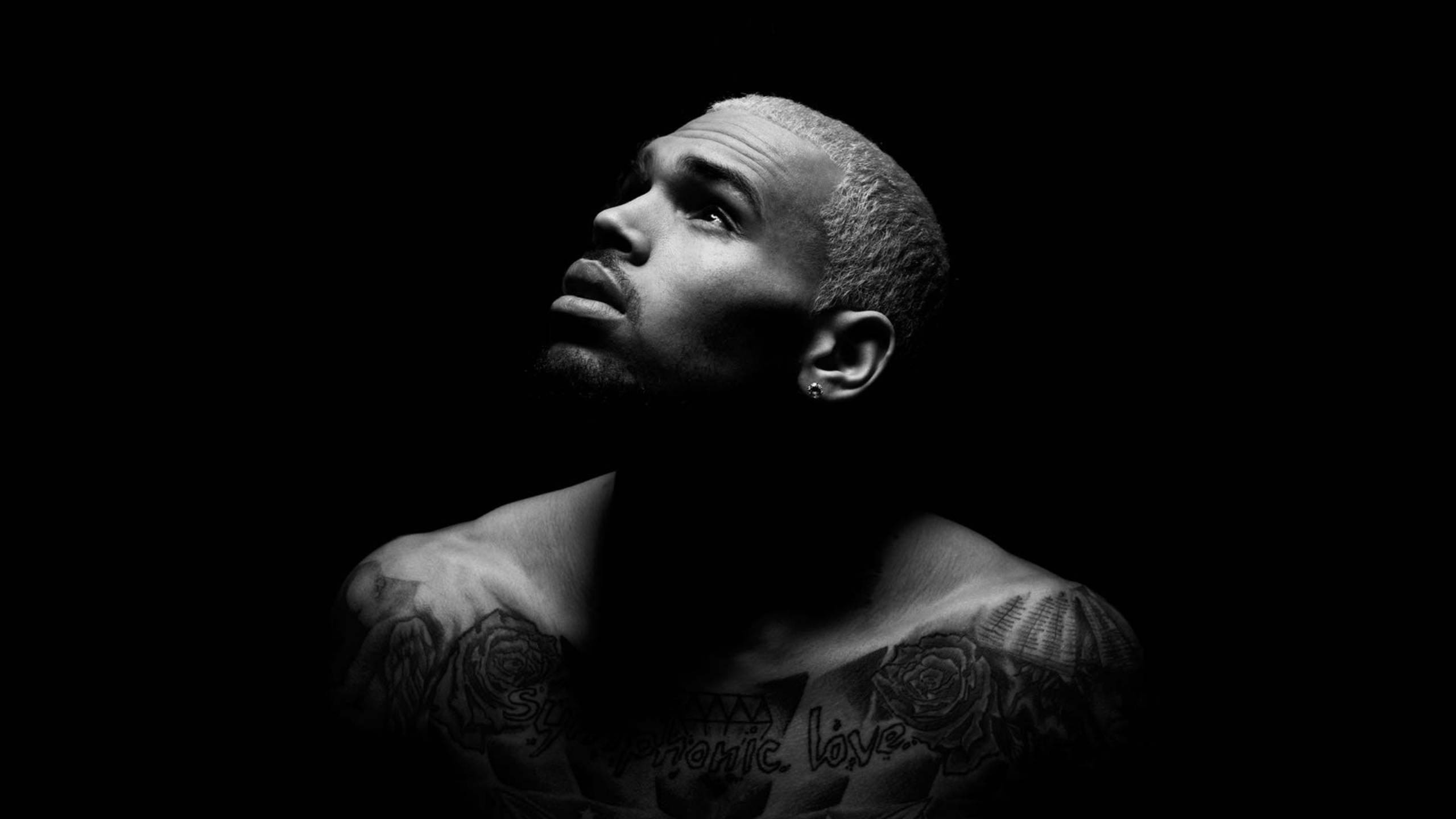 Chris Brown 桌布 壁紙 — 一個紋身男子在黑暗背景下向上凝視的黑白肖像。