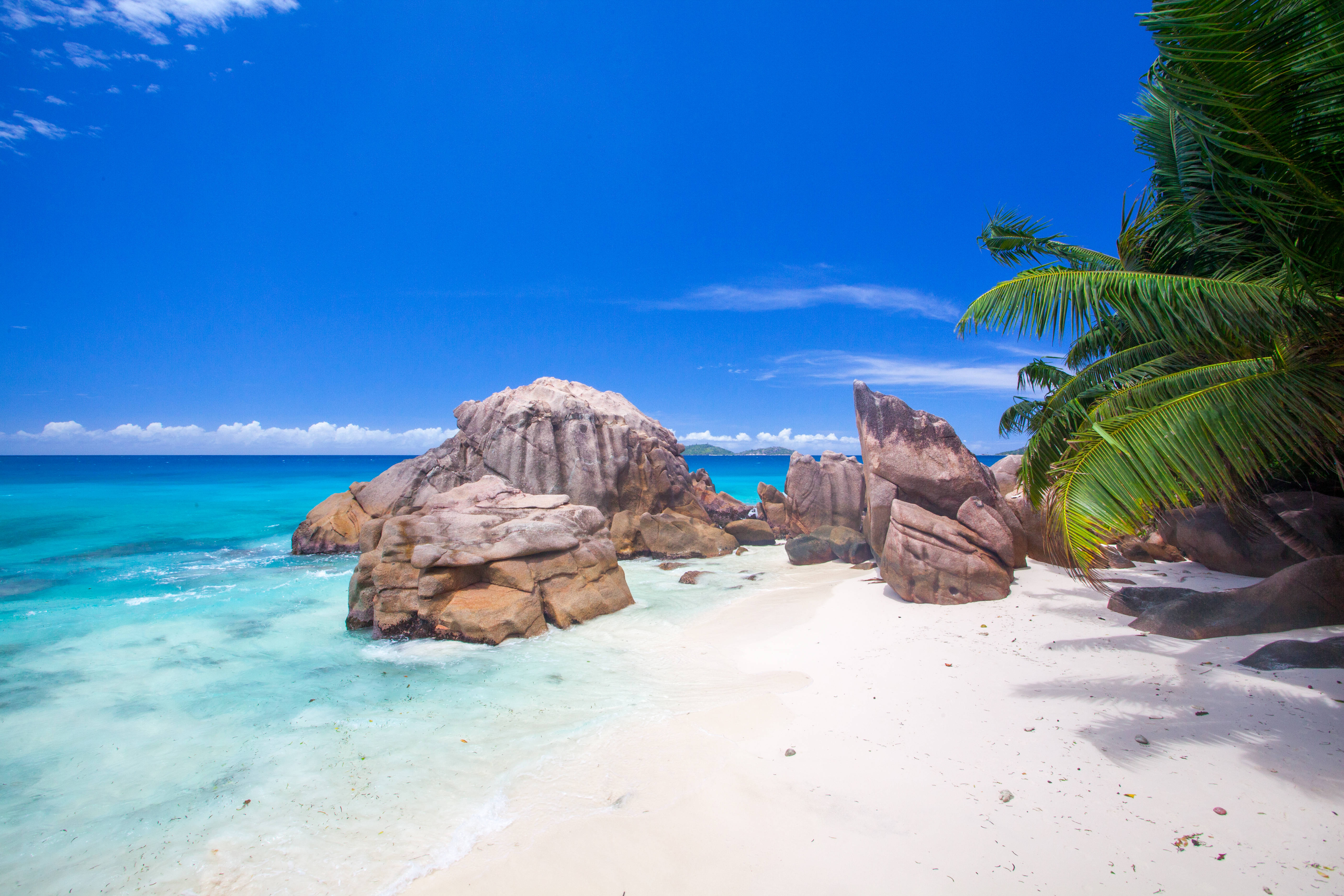 Seychelles 桌布 壁紙 — 一個純淨的熱帶海灘，擁有碧綠的海水、白色的沙灘和巨大的花崗岩巨石，在清澈的藍天下。
