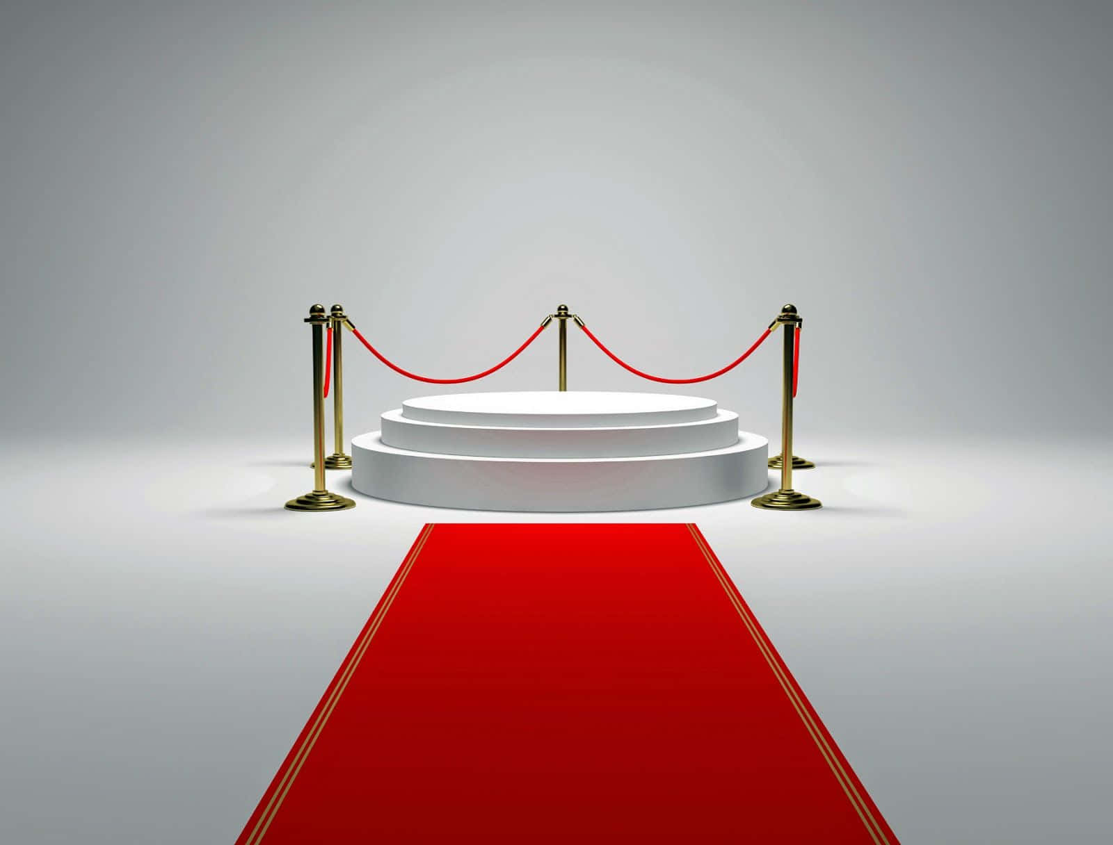 Red Carpet 桌布 壁紙 — 一個純白色圓形舞台，配有金色欄柱和紅色天鵝絨繩索，矗立在通往它的鮮豔紅地毯盡頭。