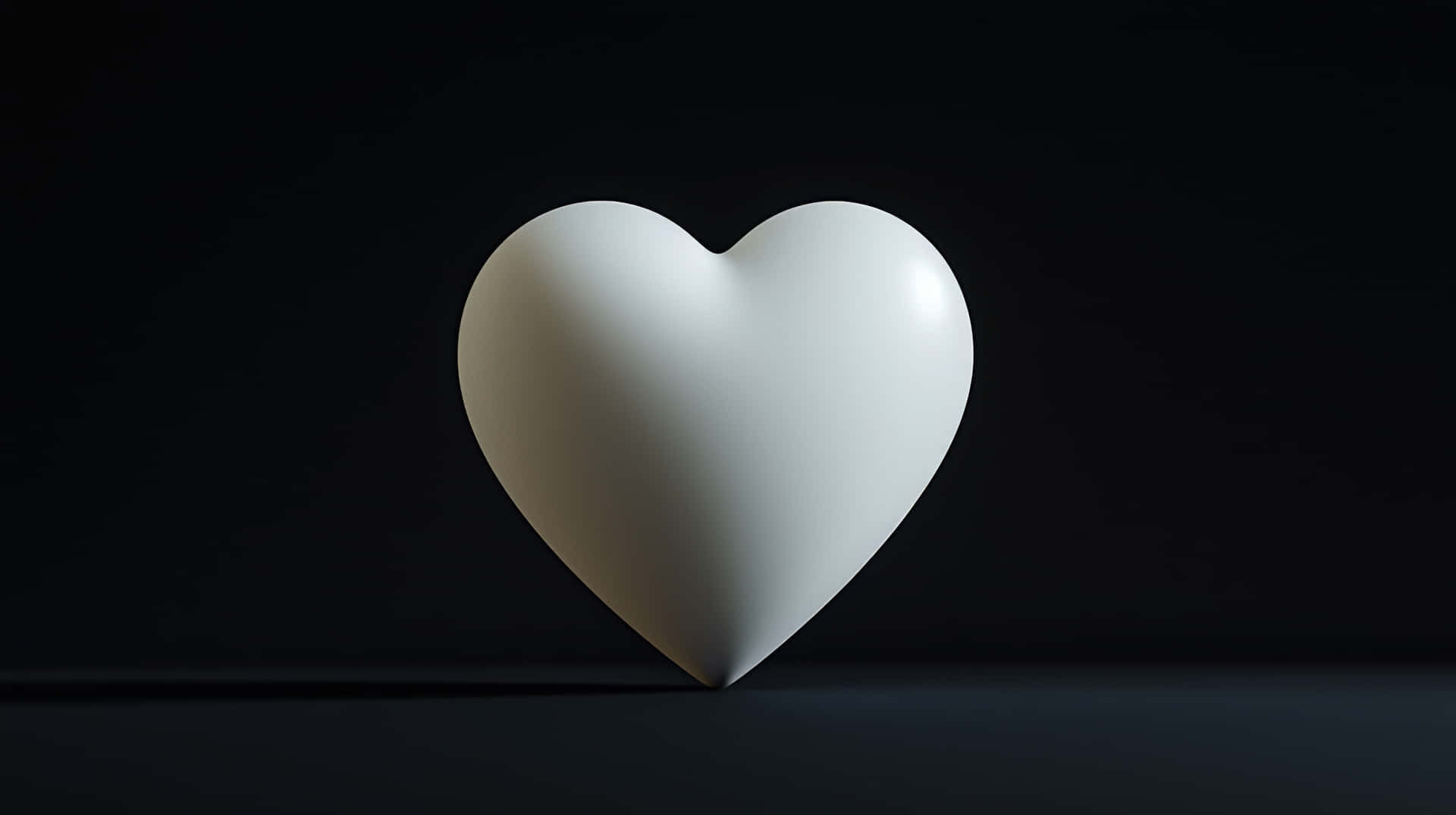 Simple white heart sculpture on dark background 壁紙 — 一個純白色的心形物體放置在黑色背景的深色表面上，光線柔和。