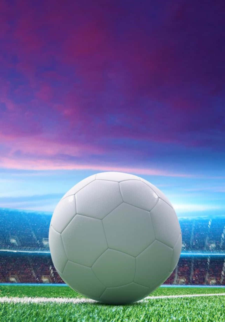 Soccer Ball 桌布 壁紙 — 一個純白色的足球放在充滿活力的綠色草地上，背景是戲劇性的紫色和藍色暮色天空，以及一個體育場。