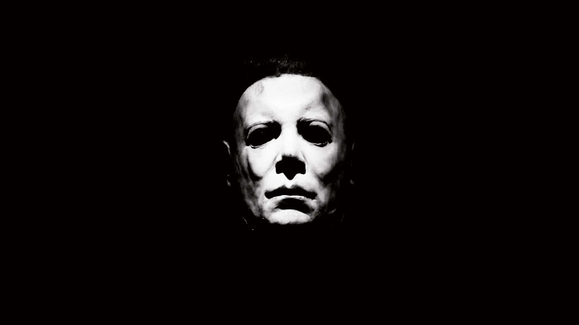 Mike Myers 桌布 壁紙 — 一個純白面具臉孔從漆黑中浮現，構成令人毛骨悚然的極簡恐怖肖像。