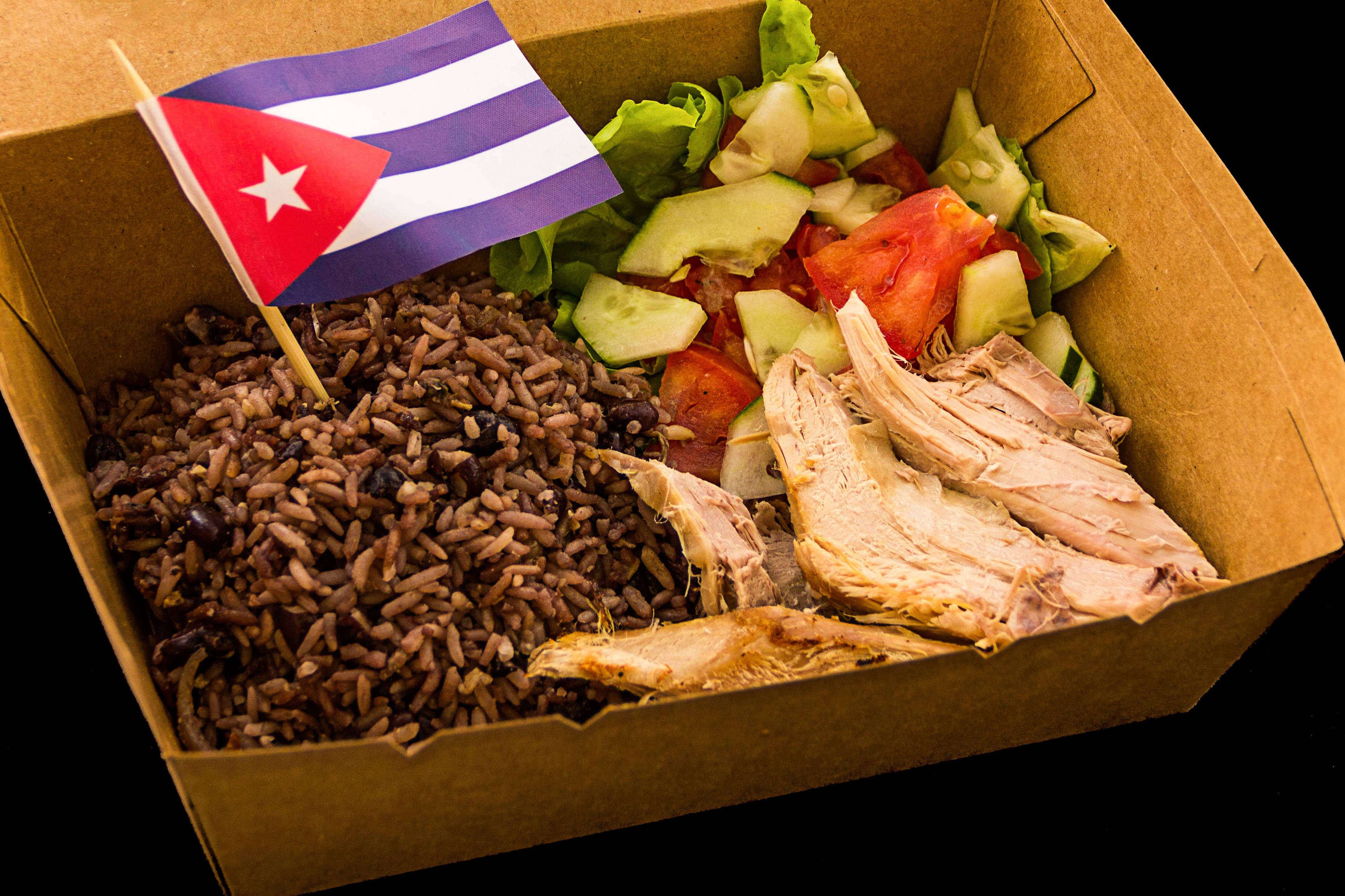 Cuban 桌布 壁紙 — 一個紙板盒裝著古巴食物，有米飯、黑豆、手撕雞肉和沙拉，上面插著一面小小的古巴國旗。
