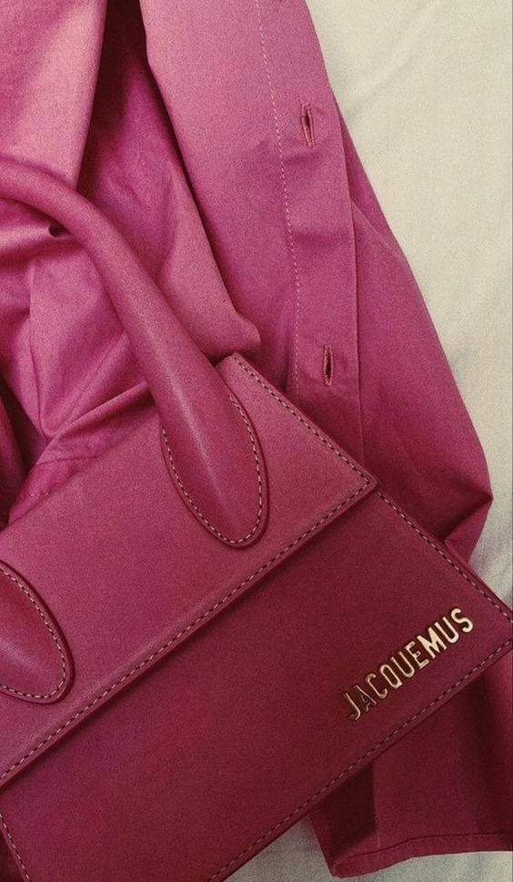 Handbag 桌布 壁紙 — 一個紫紅色皮革Jacquemus手提包的特寫，放在一件相配的紫紅色衣服上，縫線和品牌標誌清晰可見。