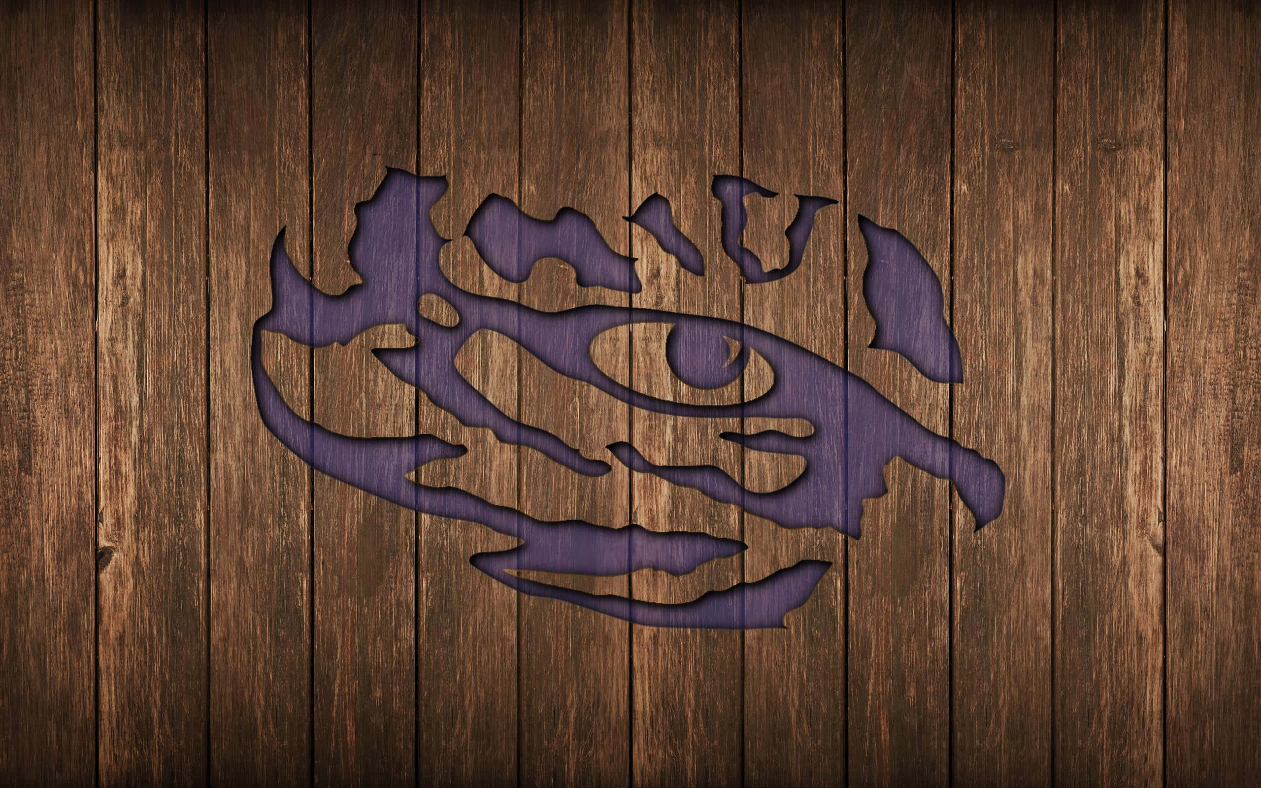 Lsu Tigers 桌布 壁紙 — 一個紫色老虎頭標誌雕刻在深色木板上，木紋和質地清晰可見。