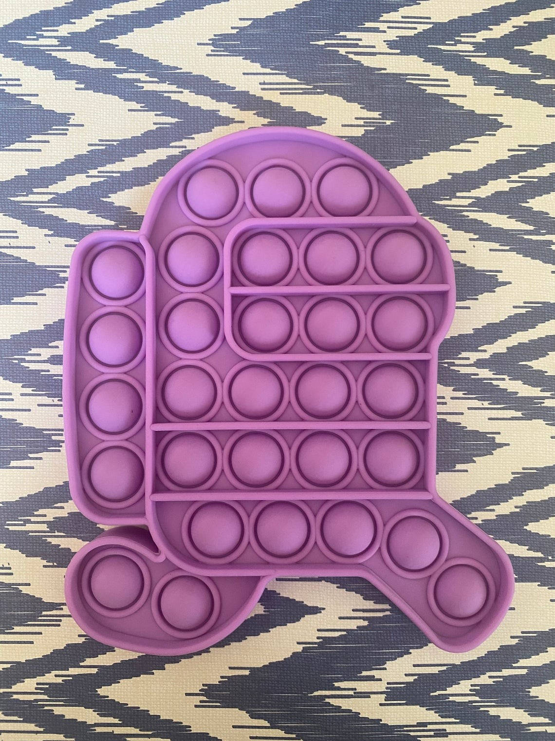 Fidget Toys 桌布 壁紙 — 一個紫色龜形按壓玩具放在幾何鋸齒紋表面上。
