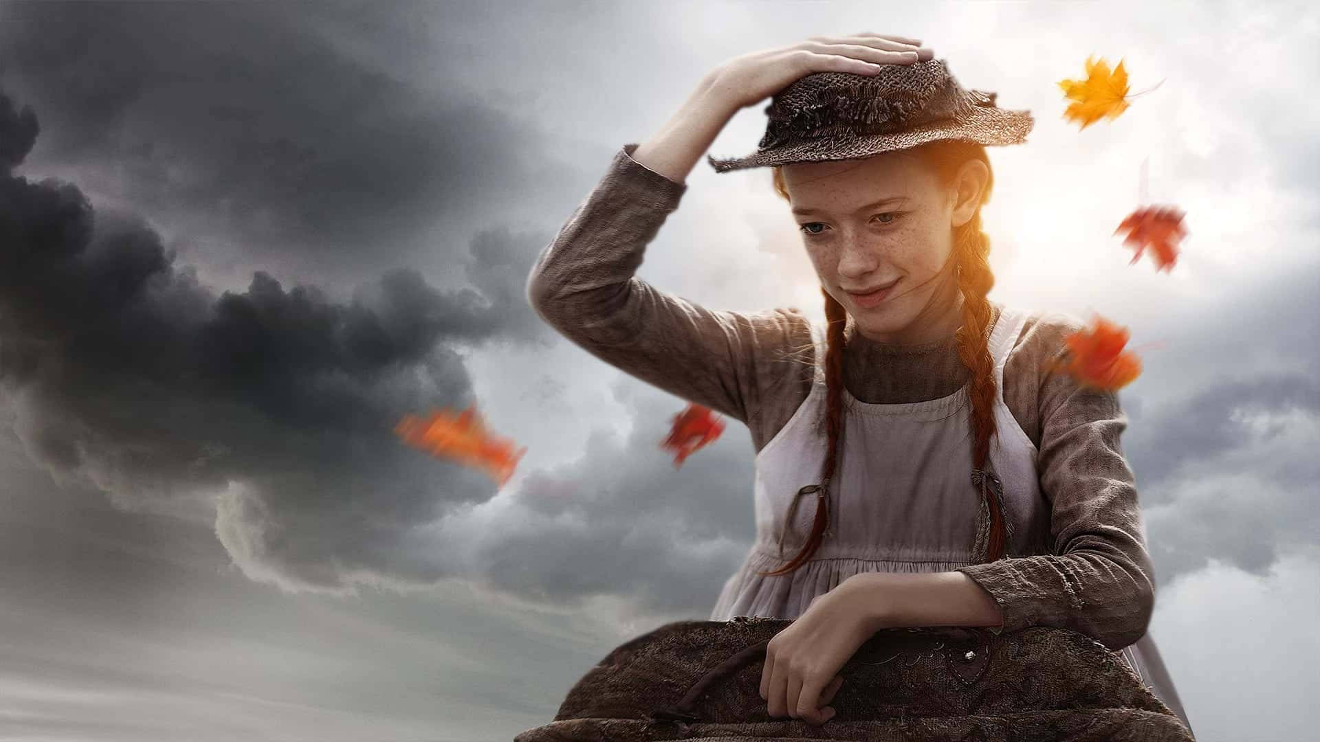 E 桌布 壁紙 — 一個紮辮子戴帽的小女孩，在暴風雨的天空下，秋葉在她周圍旋轉，她溫柔地微笑。