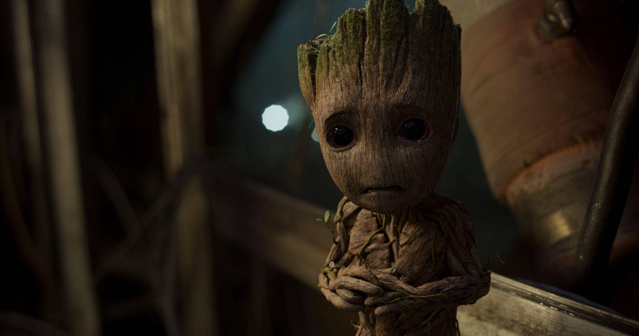 Baby Groot 桌布 壁紙 — 一個細小、像樹一樣、有大眼睛的生物，站在燈光昏暗的工業環境中，神情嚴肅而好奇。