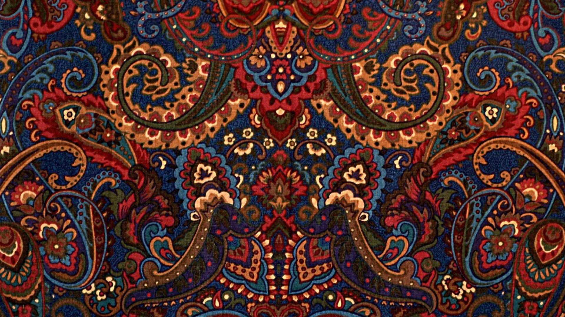 Paisley 桌布 壁紙 — 一個細節豐富的佩斯利圖案，在深藍色背景上帶有深紅、藍色和金色的漩渦花卉圖案。