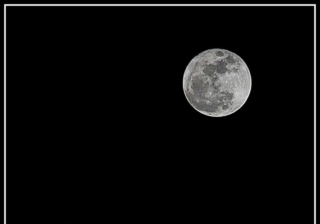 Perigee 桌布 壁紙 — 一個細節豐富的滿月，帶有隕石坑和月海，在漆黑的天空中發光，並以細白的邊框框住。