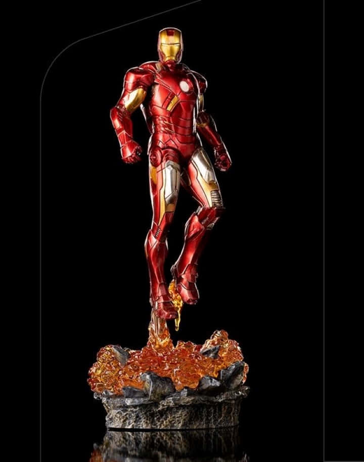 Iron Man Action Figures 桌布 壁紙 — 一個細節豐富的鋼鐵人雕像，身穿紅色和金色盔甲，動態地站在岩石底座上，帶有發光的橙色能量效果，背景為黑色。