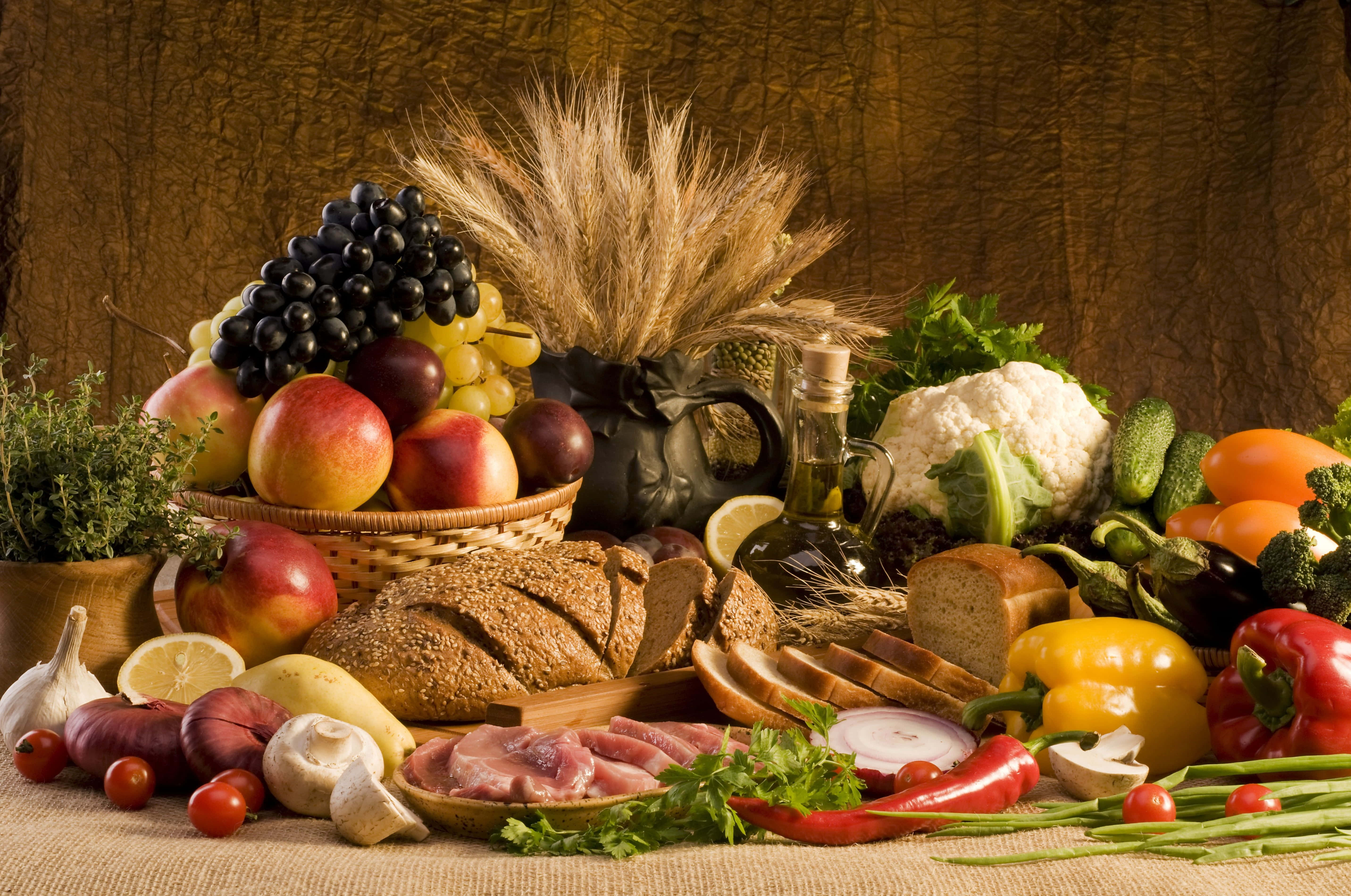 Fruits And Vegetables 桌布 壁紙 — 一個細節豐富的靜物畫，新鮮水果、蔬菜、麵包和香草擺放在麻布上，背景是帶紋理的棕色。