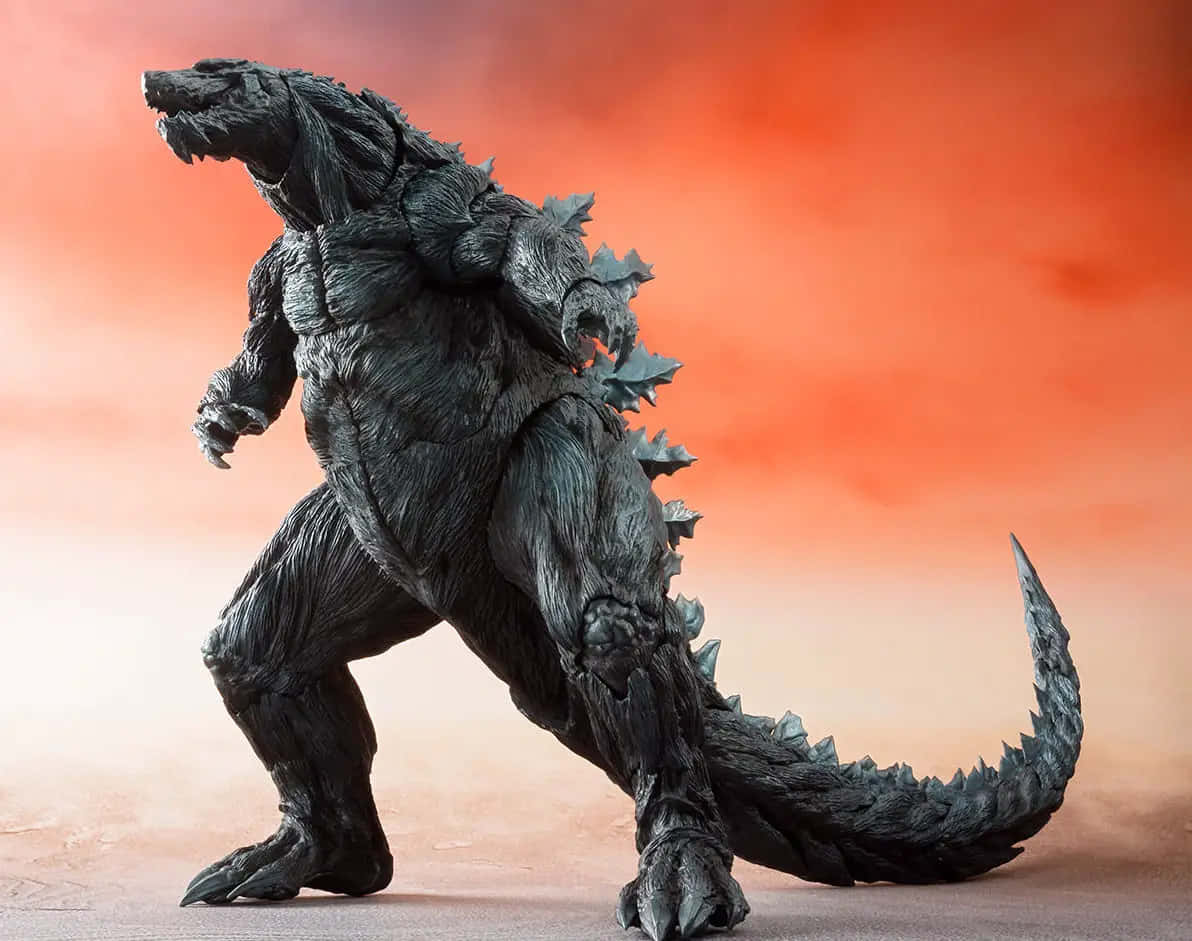 Godzilla Earth 桌布 壁紙 — 一個細節豐富的黑色哥吉拉模型以咆哮姿勢站立，背景是火熱的橙色漸變天空。