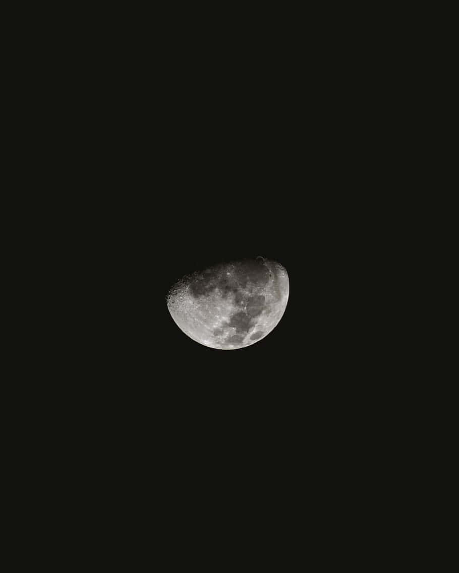 Moon Phases 桌布 壁紙 — 一個細節鮮明的月牙獨自懸掛在深邃的黑色天空中，以單色呈現出隕石坑和月海。