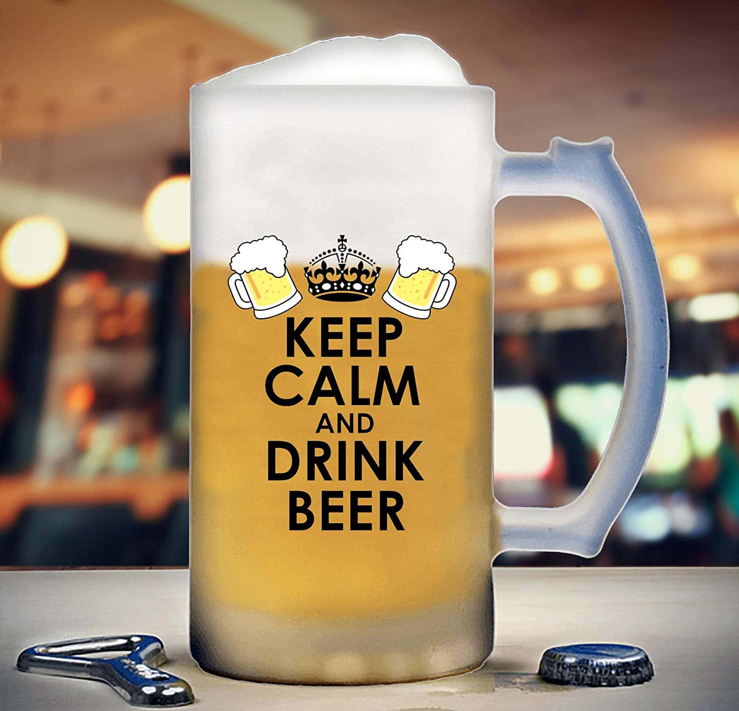 啤酒 桌布 壁紙 — 一個結霜的啤酒杯，上面有「Keep Calm and Drink Beer」文字和皇冠圖案，放在吧檯上，附近有開瓶器和瓶蓋。