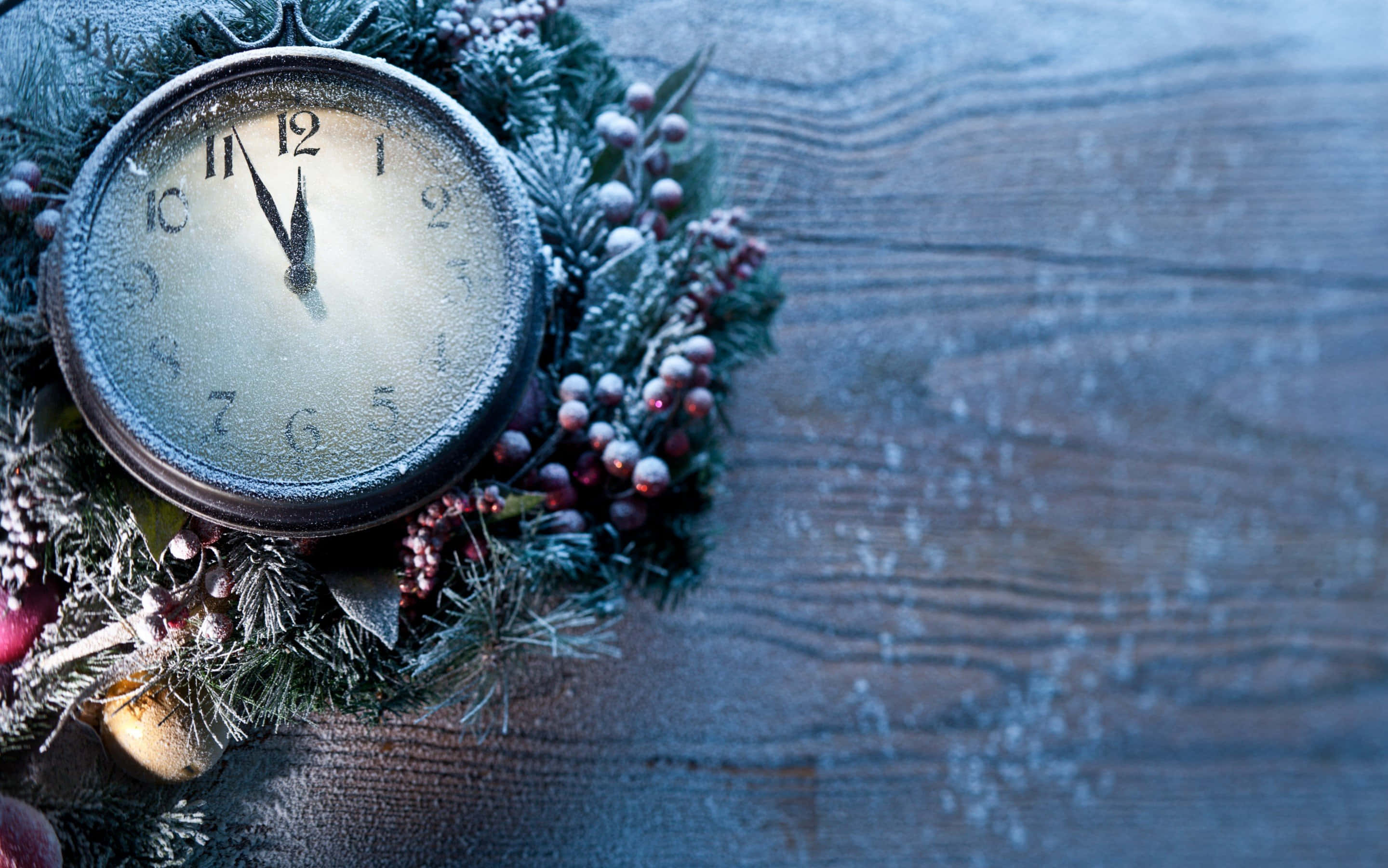 Time 桌布 壁紙 — 一個結霜的復古時鐘，藏在一個帶有莓果的雪地常綠花環中，放在一個風化的木質表面上。