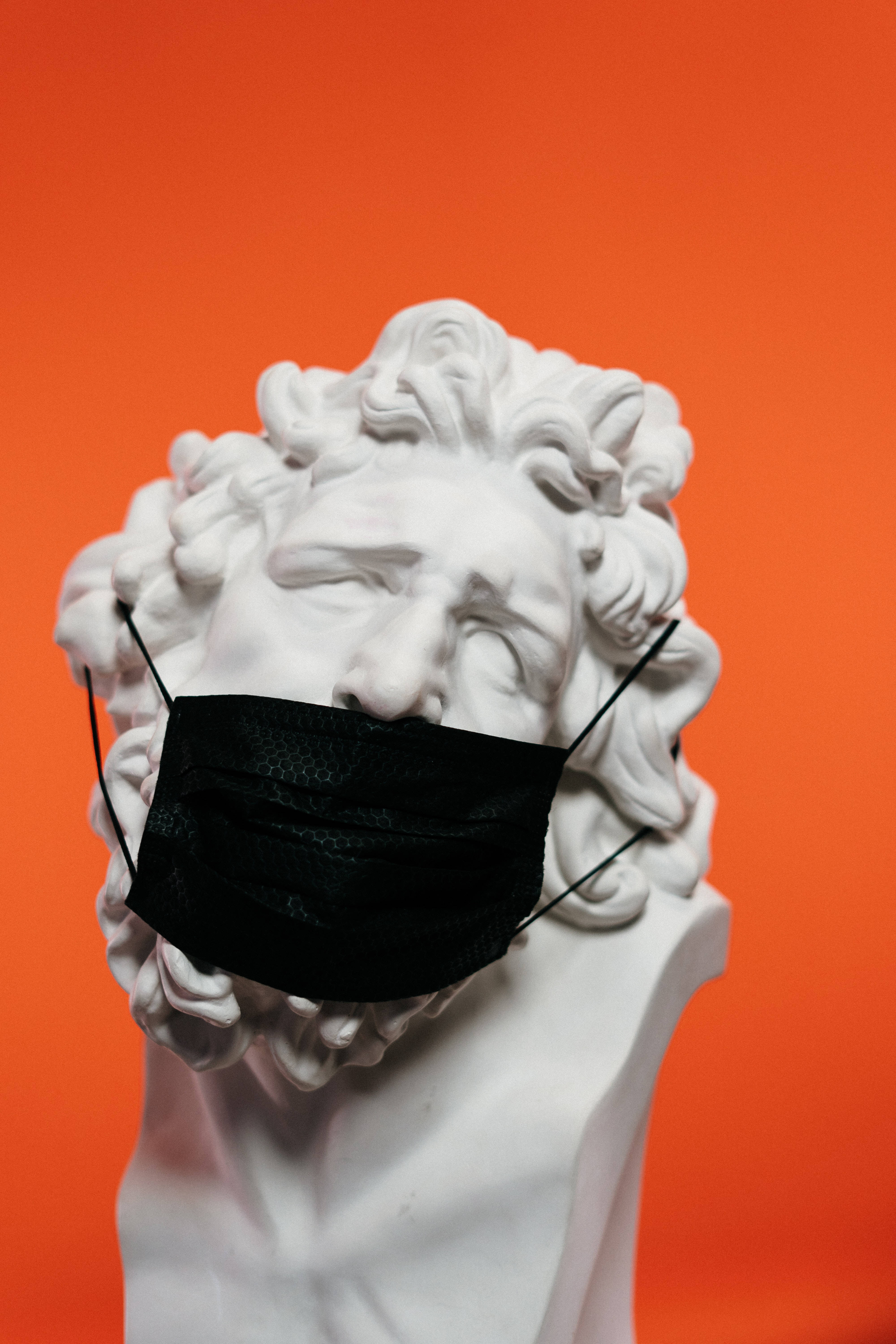 Sculpture 桌布 壁紙 — 一個經典的白色大理石半身像，捲曲的頭髮，在鮮豔的橙色背景上戴著黑色口罩。