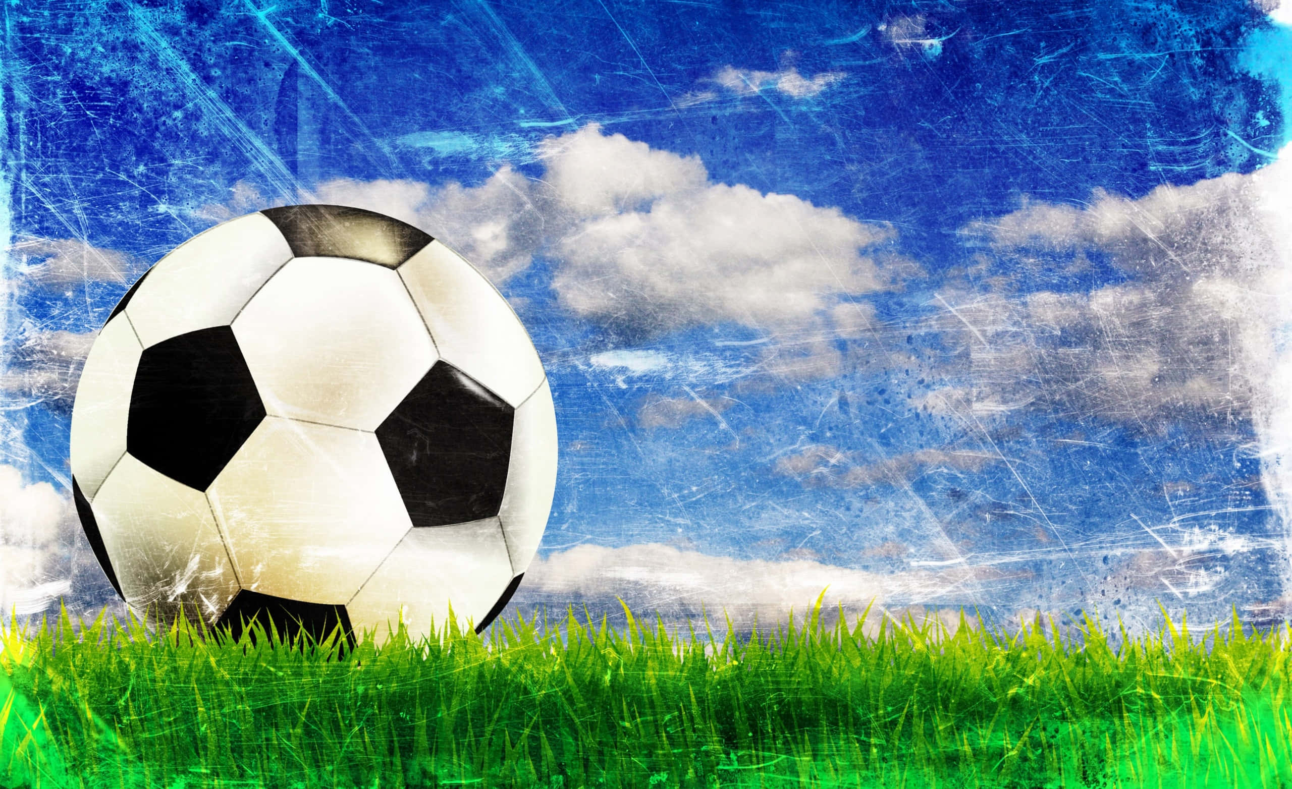 Soccer Ball 桌布 壁紙 — 一個經典的黑白足球放在充滿活力的綠色草地上，背景是有紋理的藍天和蓬鬆的白雲。