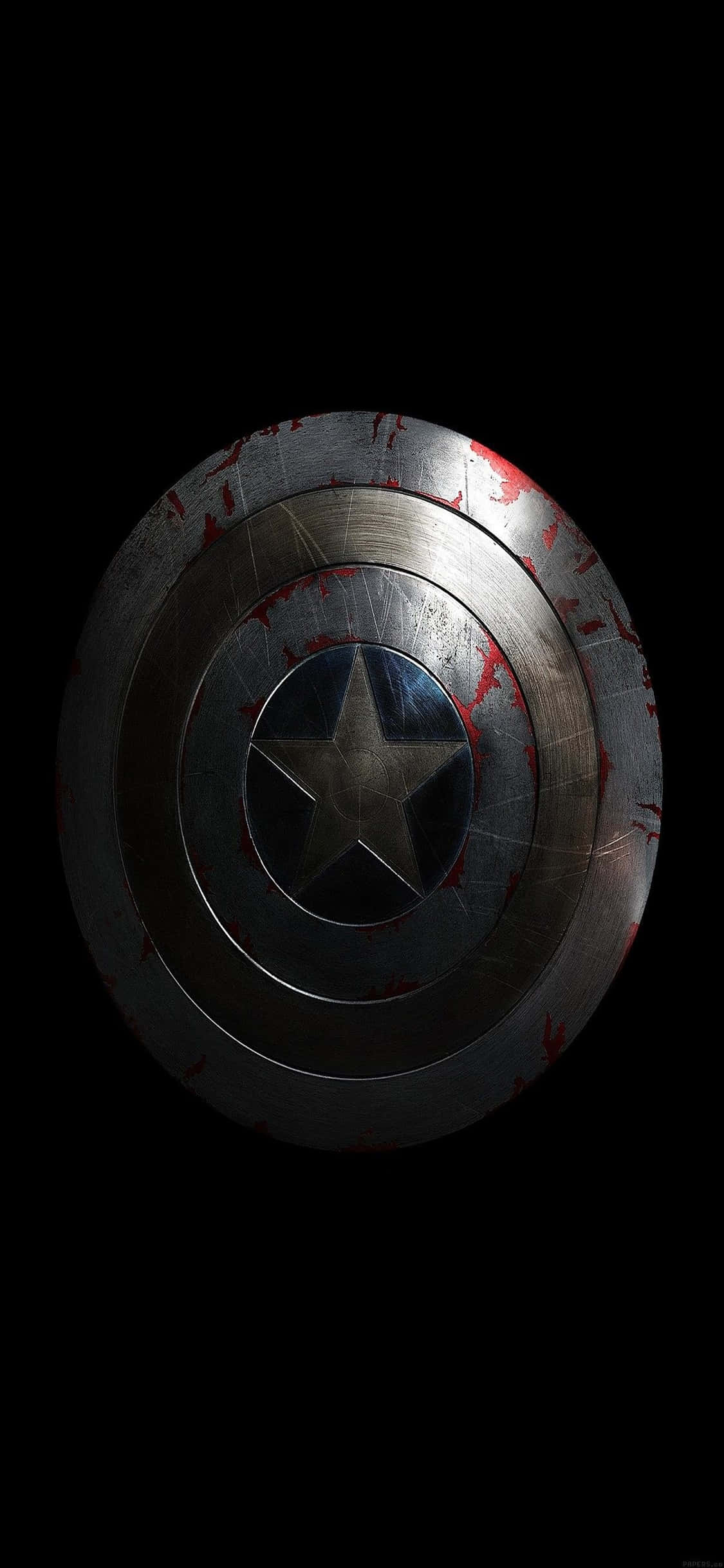 iPhone Xs Marvel's Avengers 桌布 壁紙 — 一個經歷戰鬥、沾滿血跡的美國隊長盾牌，在黑色虛空中戲劇性的燈光下發光。