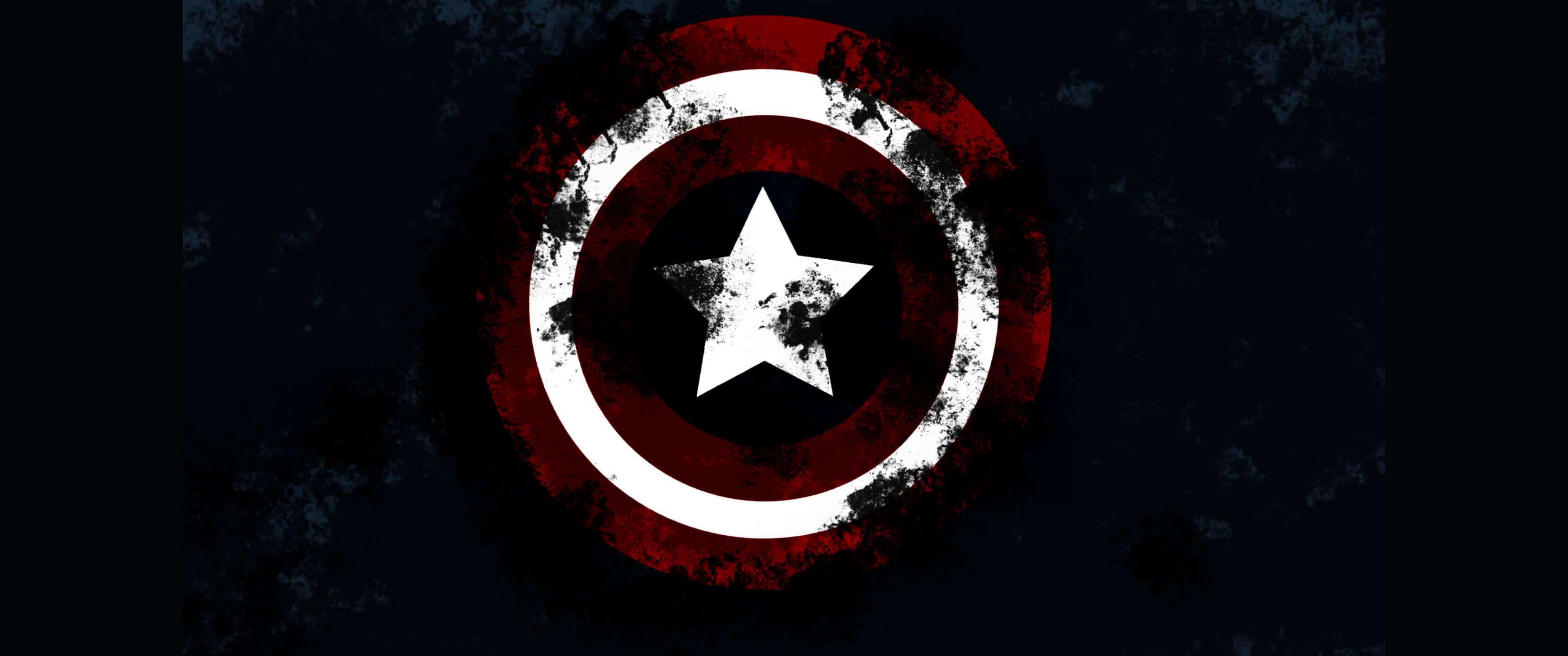 3440x1440p Captain America 桌布 壁紙 — 一個經風化的美國隊長盾牌，帶有紅、白、藍色圓環，中央有一顆星，置於深色紋理背景上。