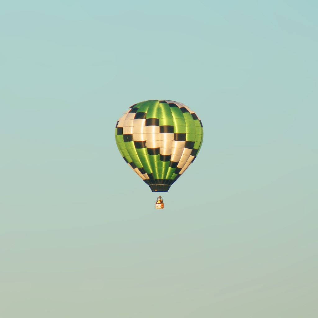 Hot Air Balloon 桌布 壁紙 — 一個綠色、黑色和奶油色格紋熱氣球在柔和粉彩天空下寧靜漂浮。