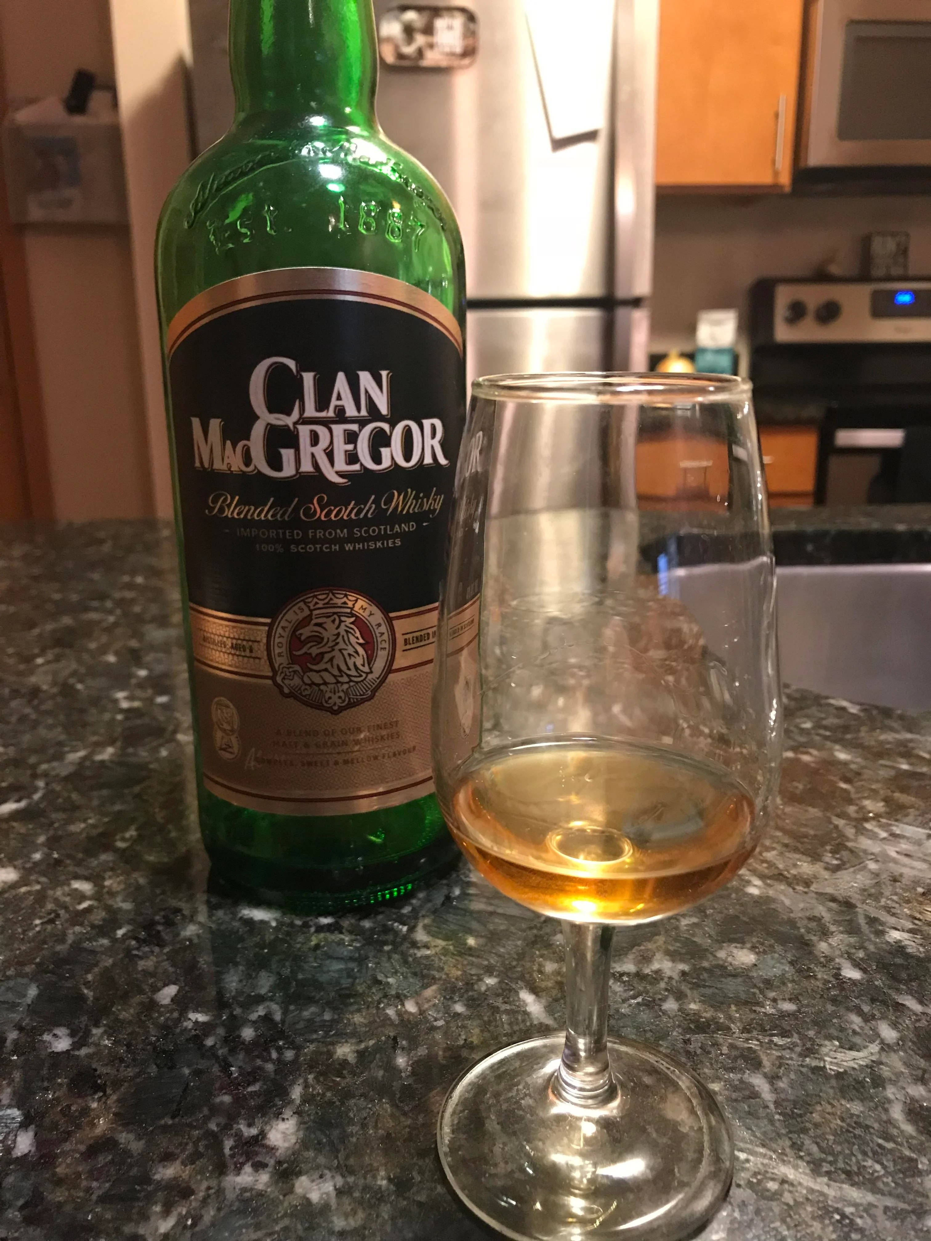 Whiskey 桌布 壁紙 — 一個綠色Clan MacGregor威士忌酒瓶和一個裝有琥珀色液體的玻璃杯放在廚房有斑點的檯面上。