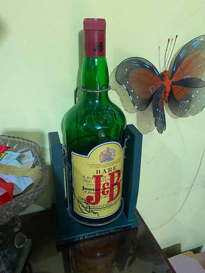 drinks 桌布 壁紙 — 一個綠色J&B Rare蘇格蘭威士忌酒瓶放在藍色底座上，置於木桌上，旁邊有裝飾性蝴蝶牆藝。