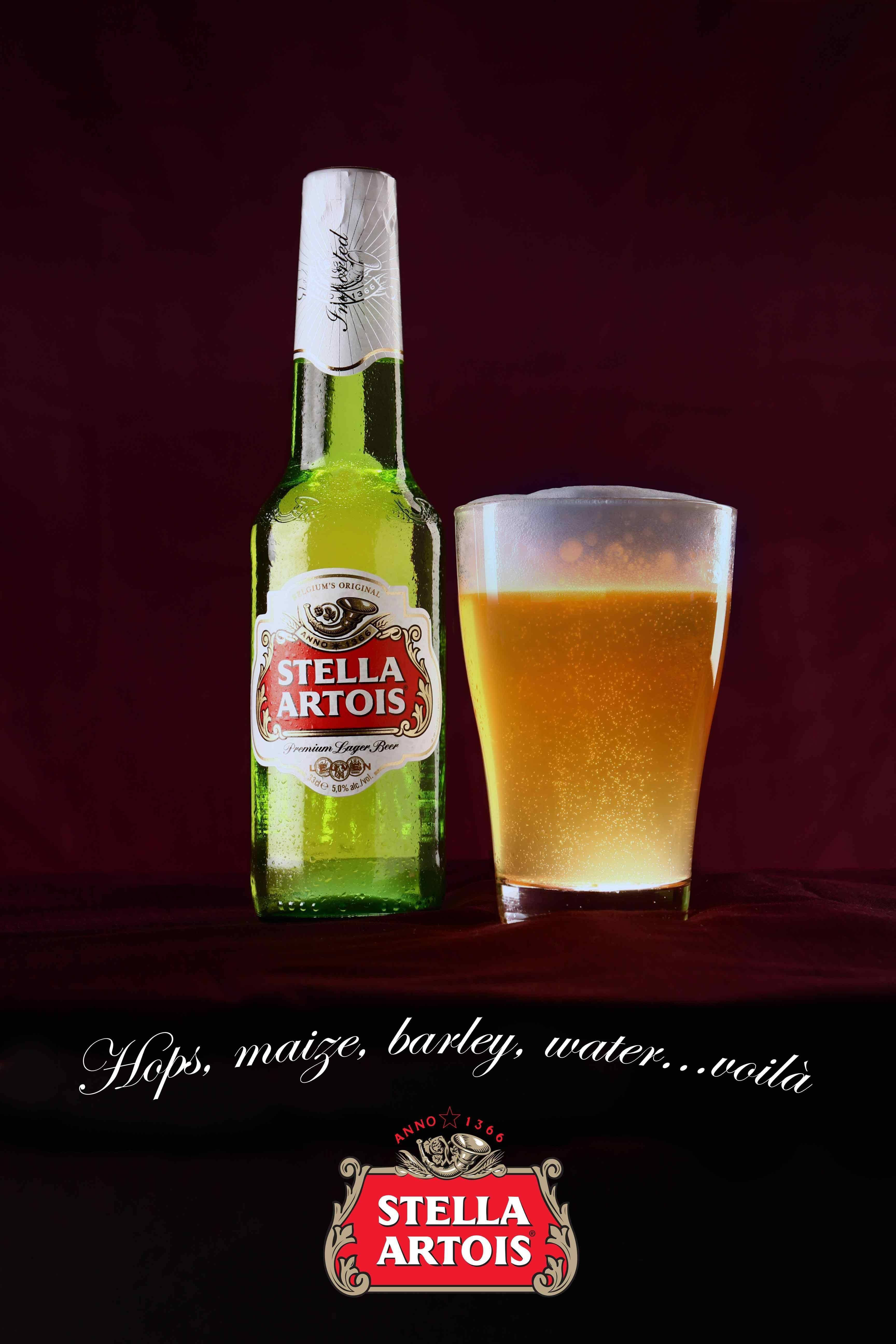 Drink 桌布 壁紙 — 一個綠色Stella Artois啤酒瓶和一個泡沫玻璃杯放在深紅色天鵝絨表面上，背景是深栗色。