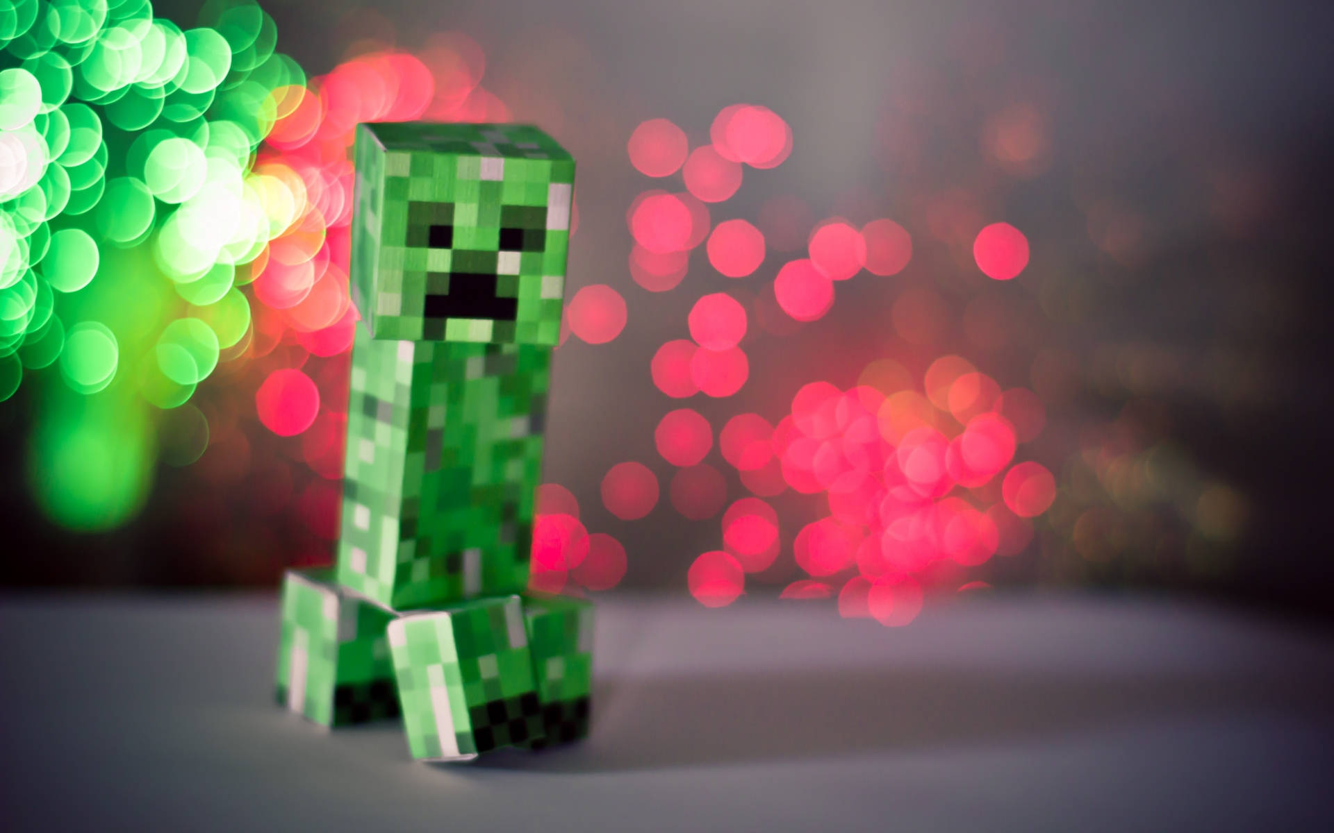 Creeper 桌布 壁紙 — 一個綠色像素風格的苦力怕公仔坐在紅色和綠色燈光的鮮豔散景背景前。